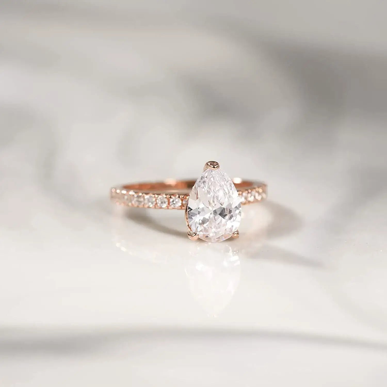 Rose gold pear-shaped diamond ring with sparkling accents, perfect for elegant accessorizing or special occasions.