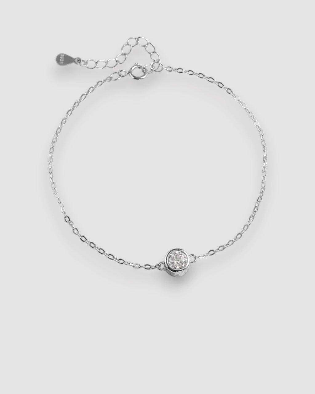 Silver bracelet with a small round gemstone on a light gray background