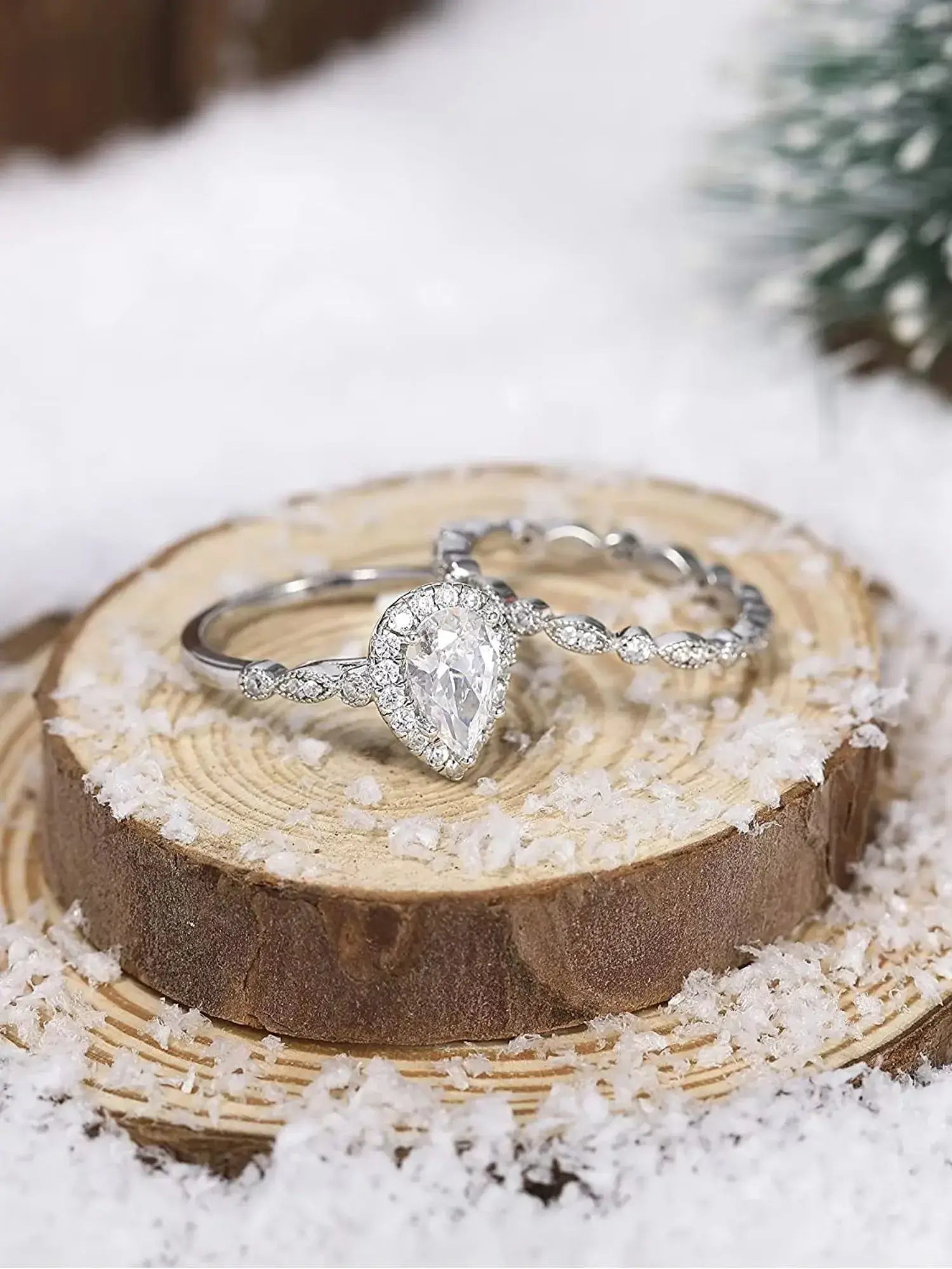 1.5CT teardrop CZ two ring set on rustic wood, adorned with sparkling cubic zirconia, perfect as an engagement or gift ring.