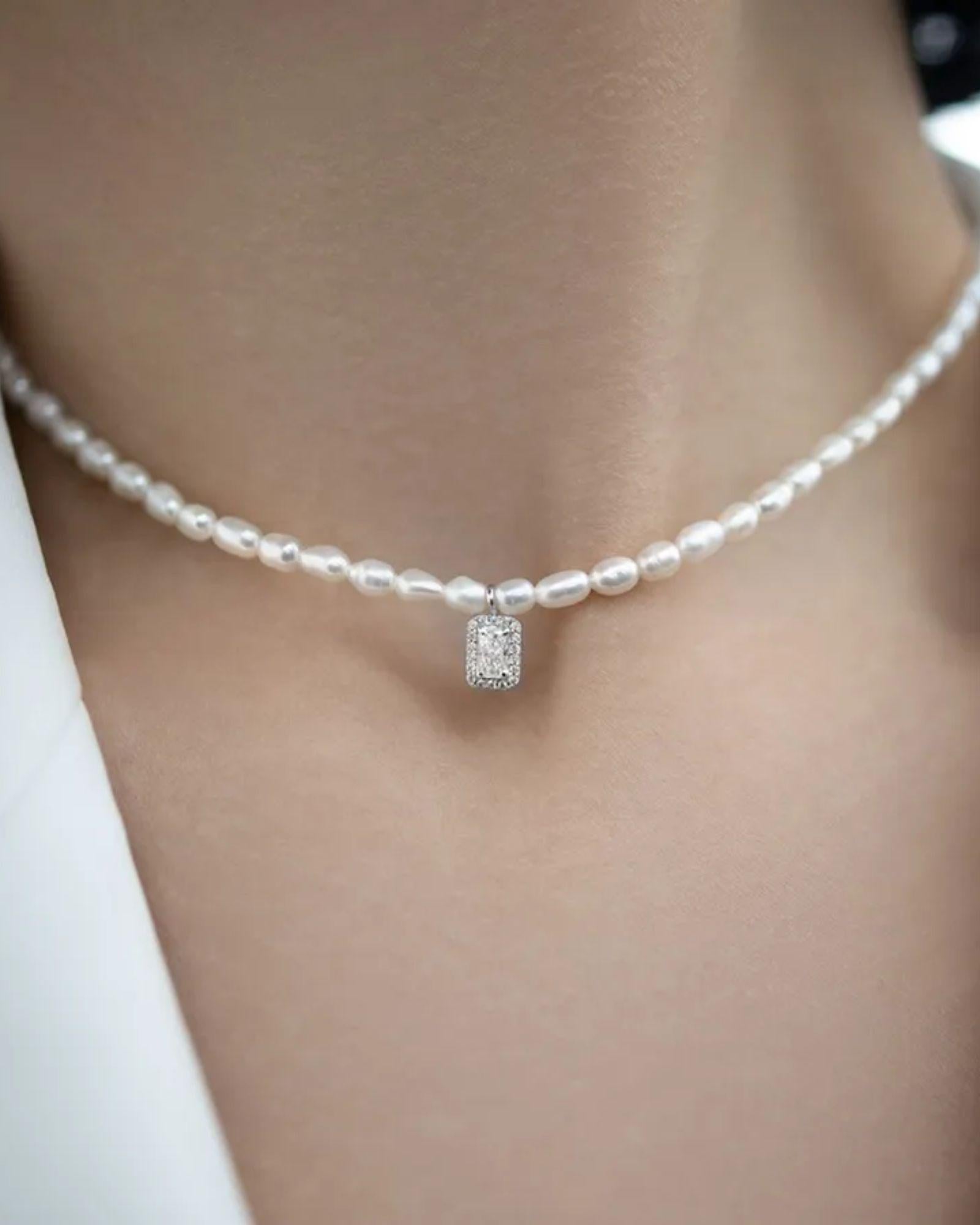 Pearl necklace with a diamond pendant on a neutral background