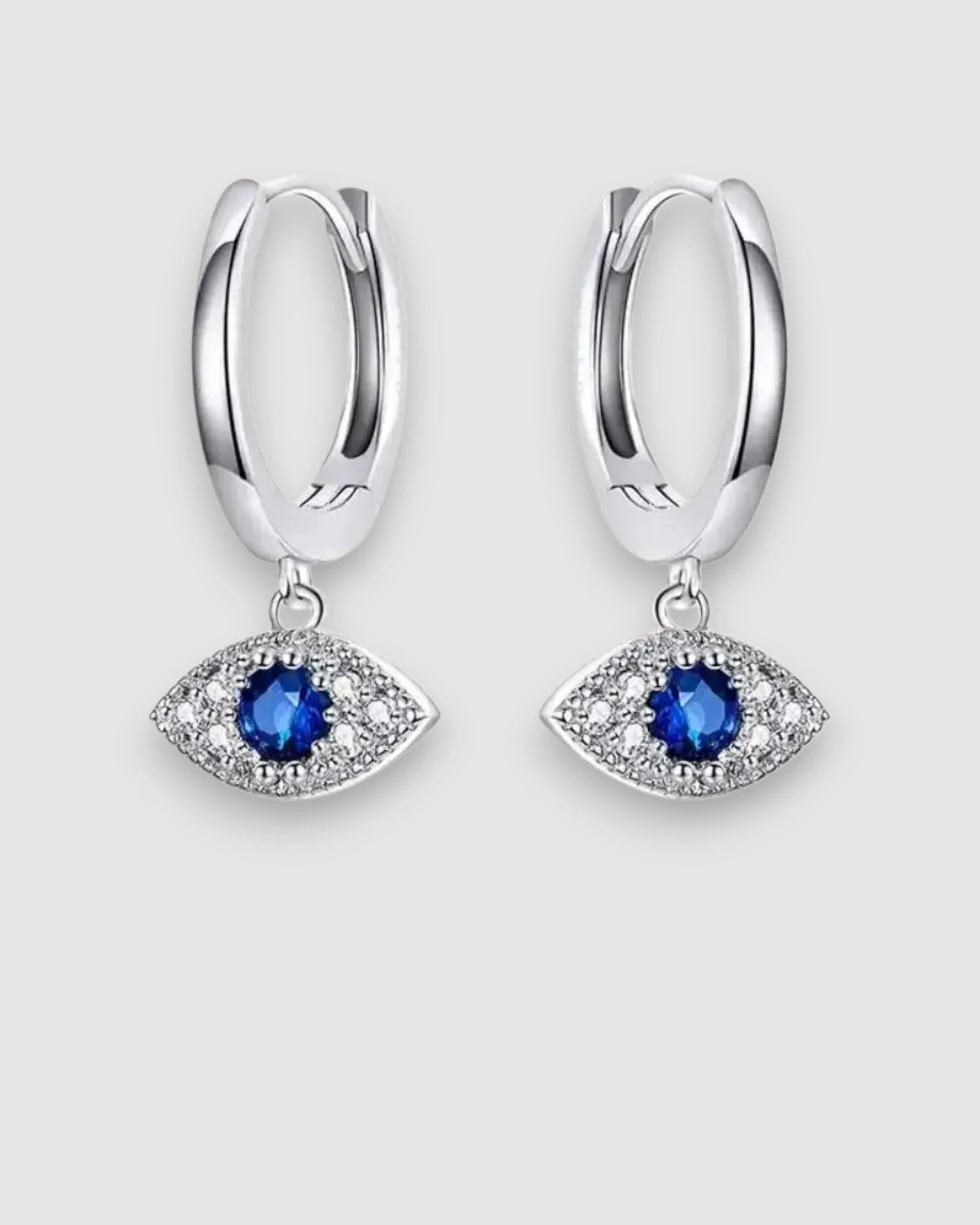 Silver hoop earrings with blue gemstone eye designs on a light gray background