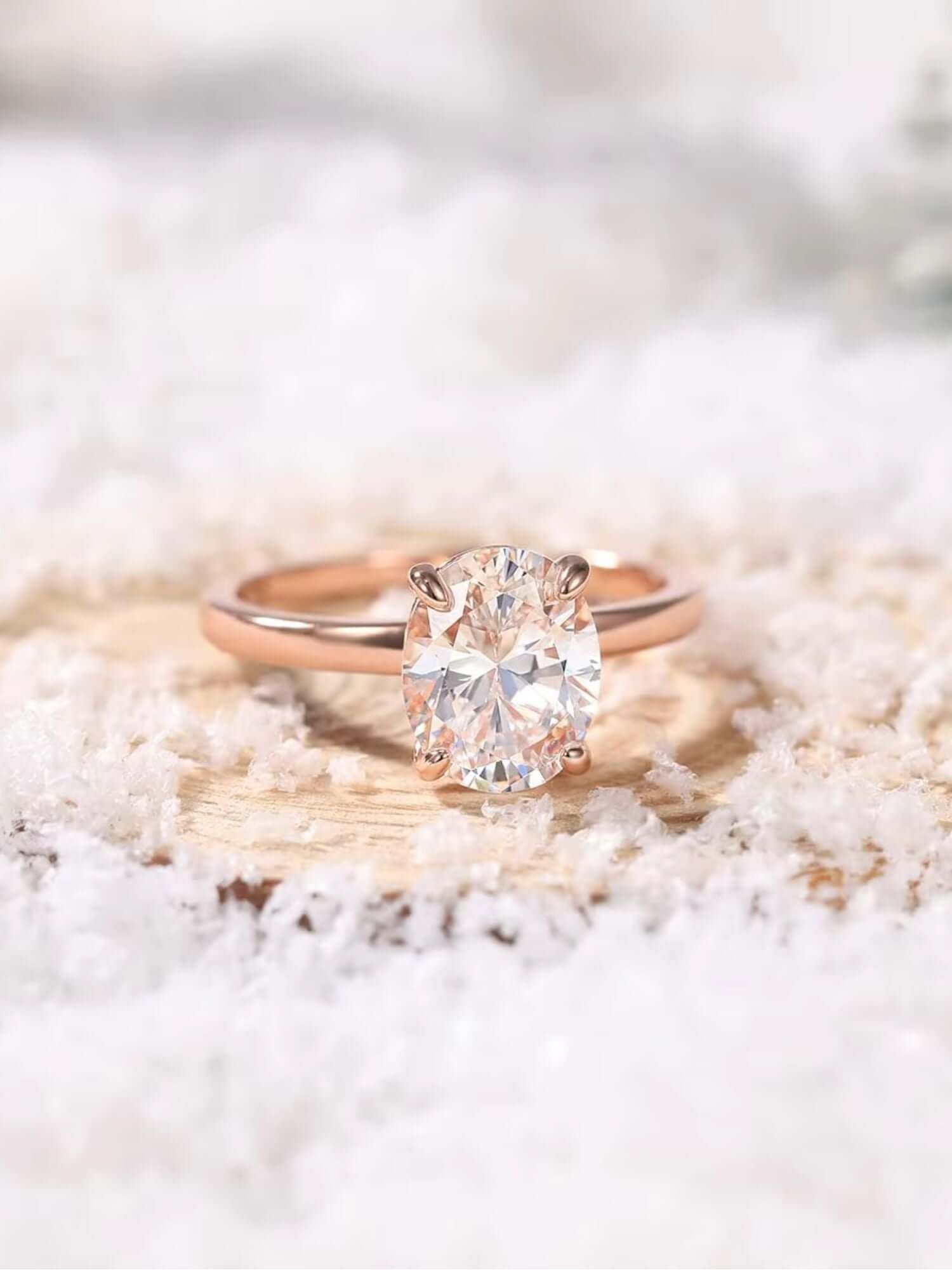3CT oval cut cubic zirconia ring on a wooden surface surrounded by snow, showcasing its elegant design and sparkle.