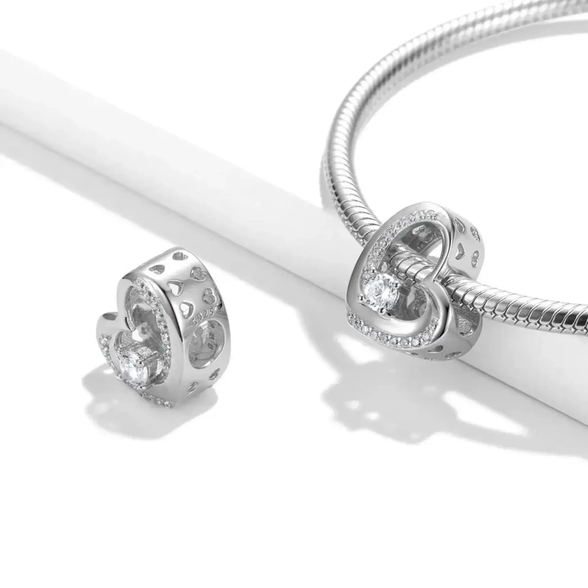 Silver bracelet with heart-shaped charm on a white background