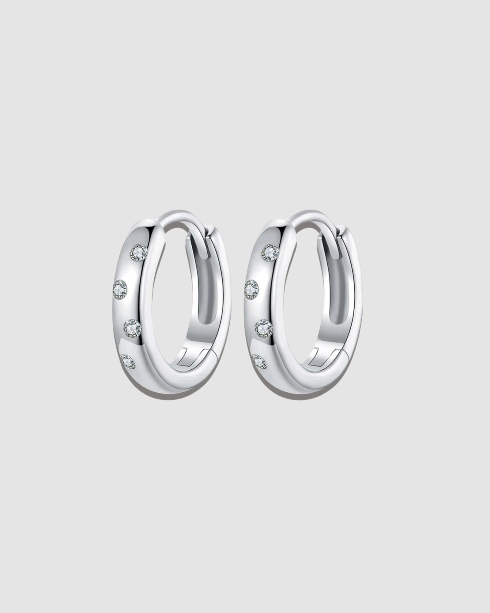 Pair of silver hoop earrings with small stones on a white background