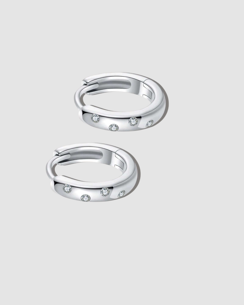Pair of silver hoop earrings with small stones on a white background