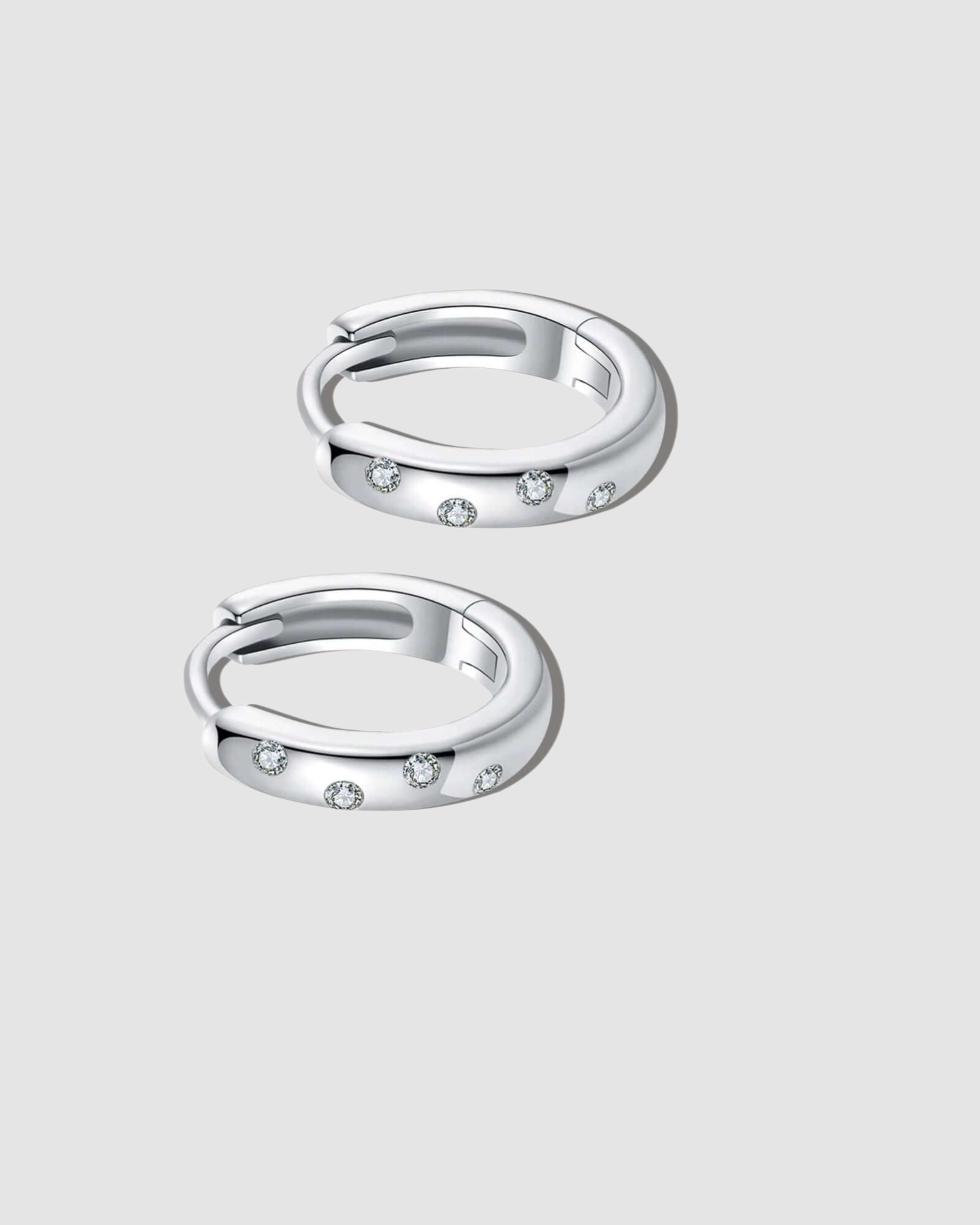 Pair of silver hoop earrings with small stones on a white background