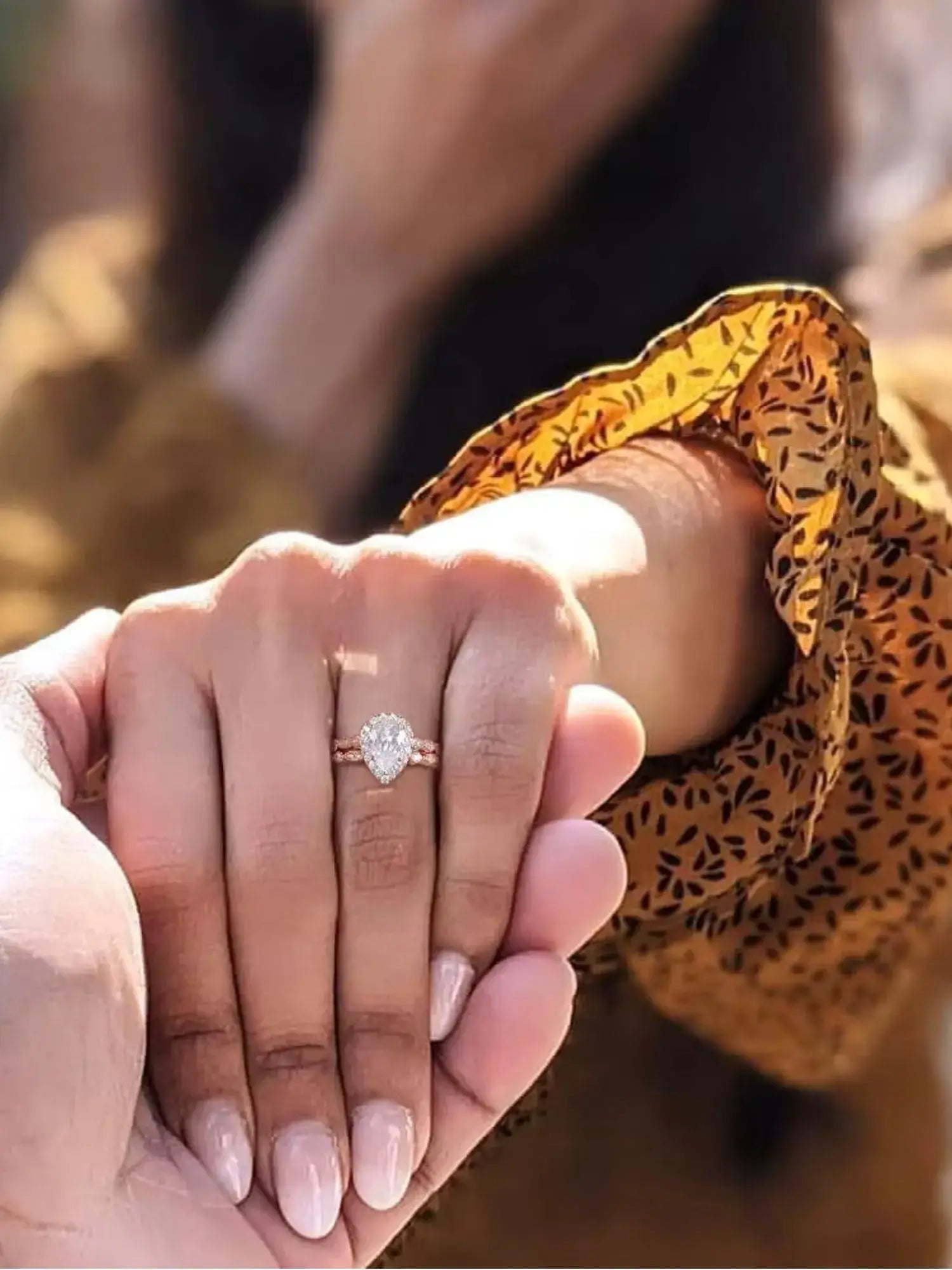 Close-up of a hand wearing a 1.5CT teardrop CZ two ring set, held by another hand, showcasing its elegant design.