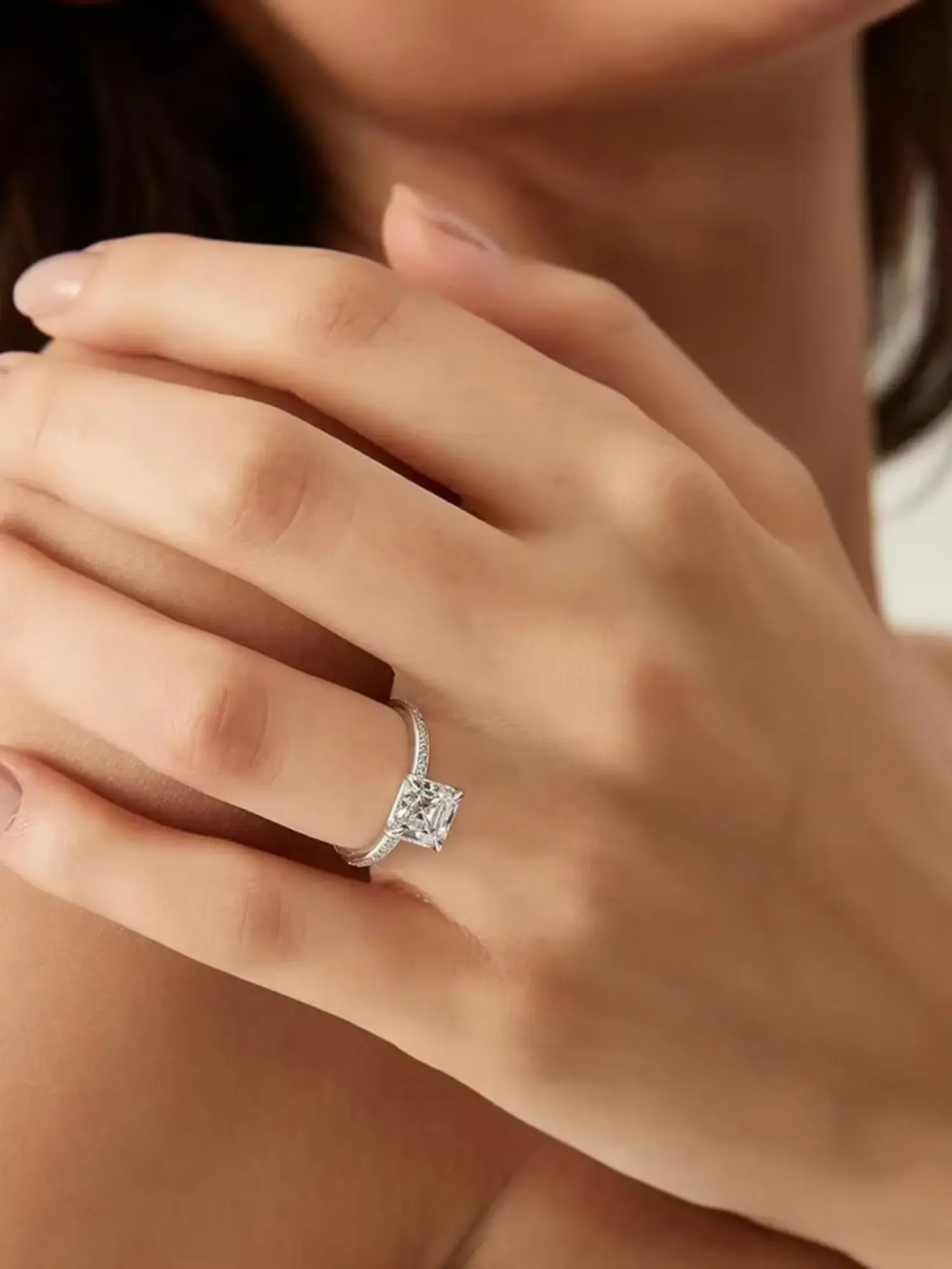 Close-up of a hand wearing a 2CT Asscher Cut CZ wedding ring, showcasing its vintage-inspired charm.