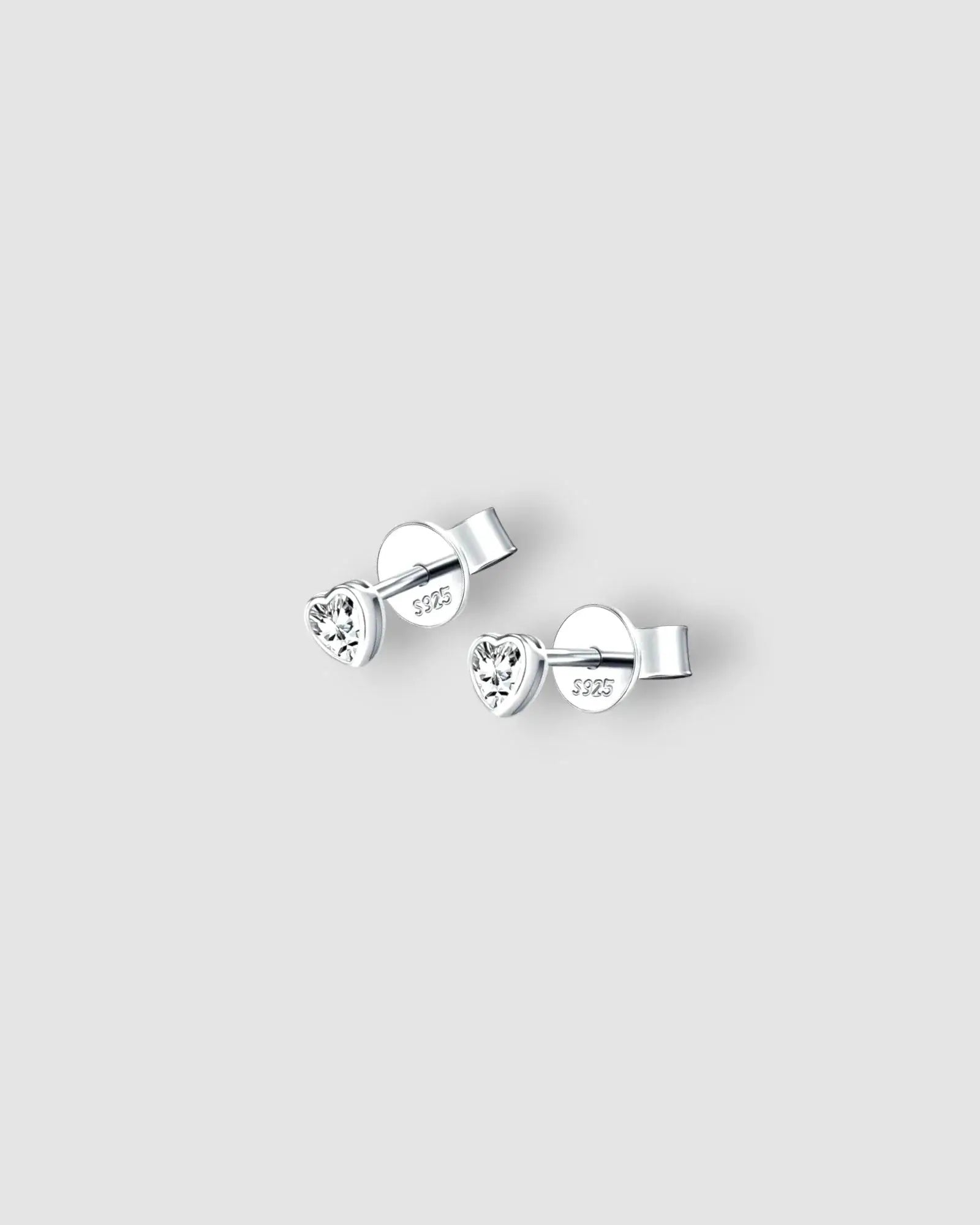 Pair of silver heart-shaped stud earrings on a light gray background