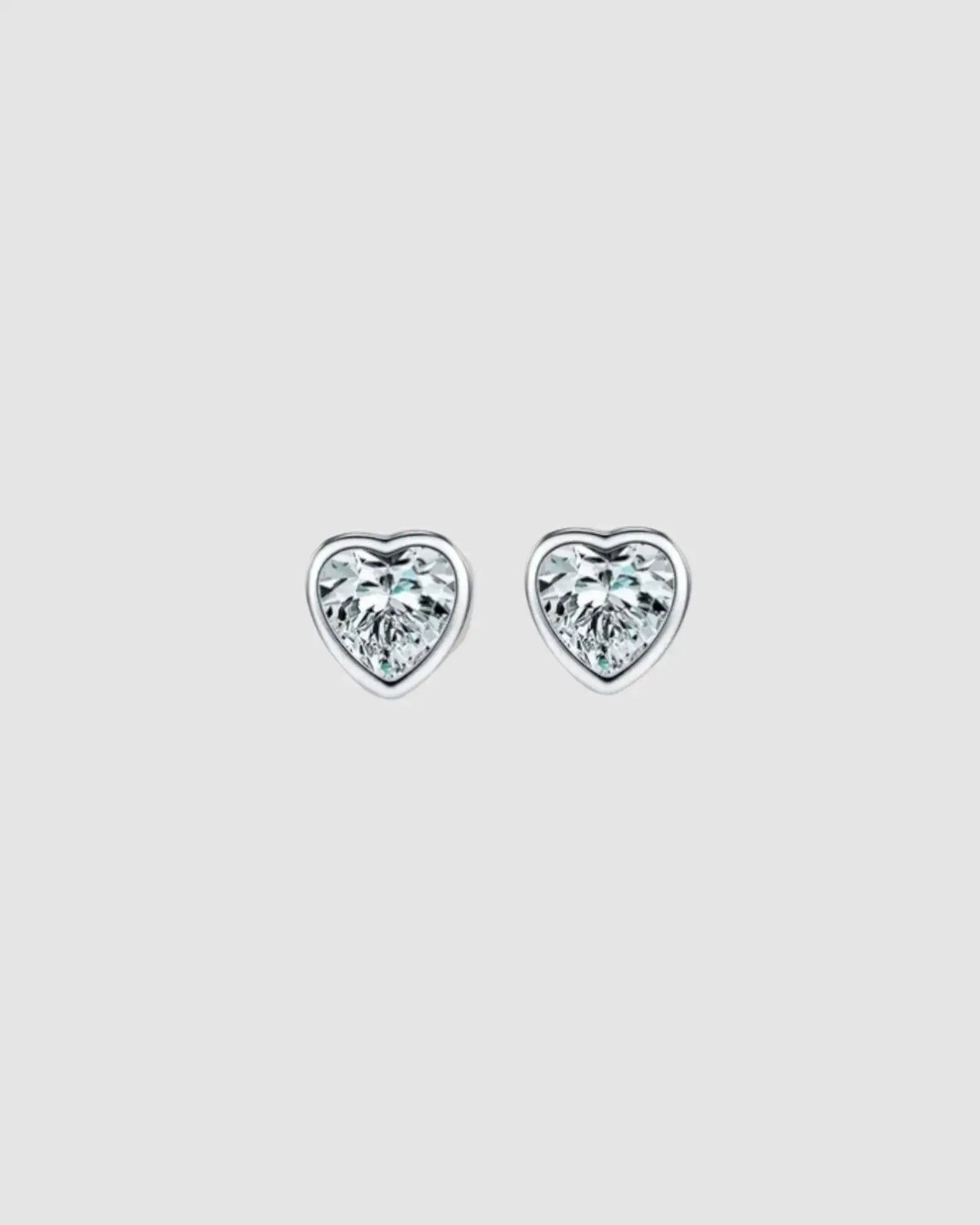 Heart-shaped diamond stud earrings on a light gray background