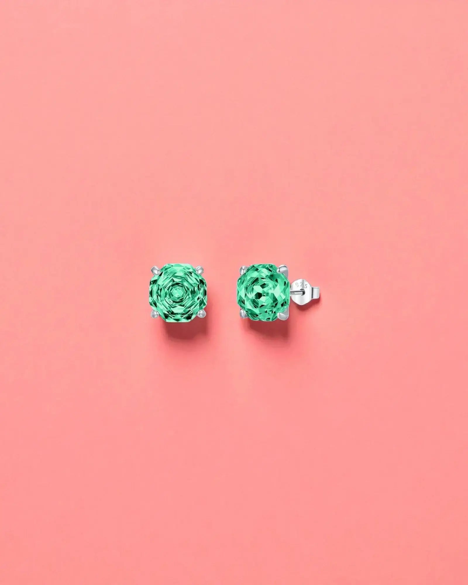 Pair of green gemstone earrings on a pink background