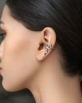 Close-up of an ear with a silver earring against a neutral background