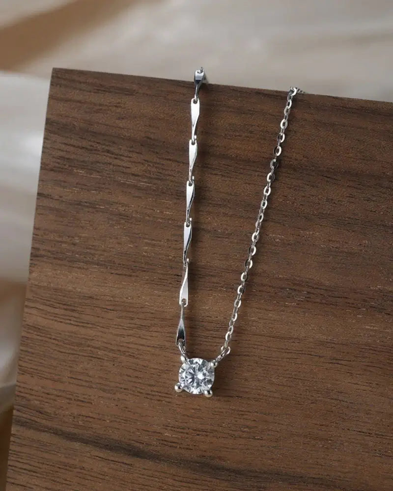Bling pendant necklace showcasing a chic cable chain with a dazzling cubic zirconia pendant on wood background.