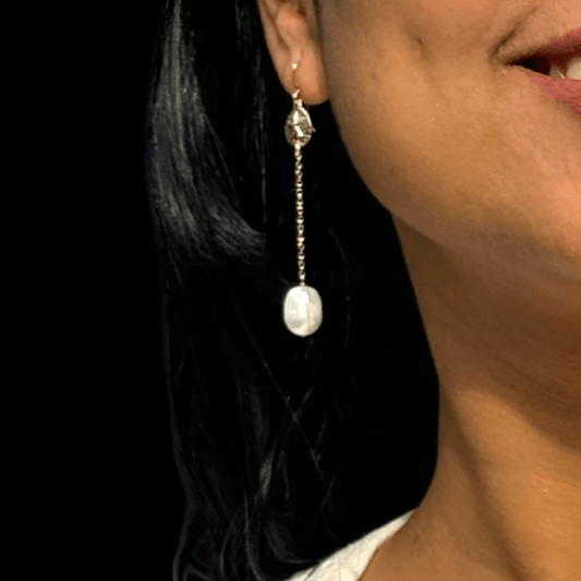 A woman wearing an elegant long freshwater pearl earring made in 14k gold filled