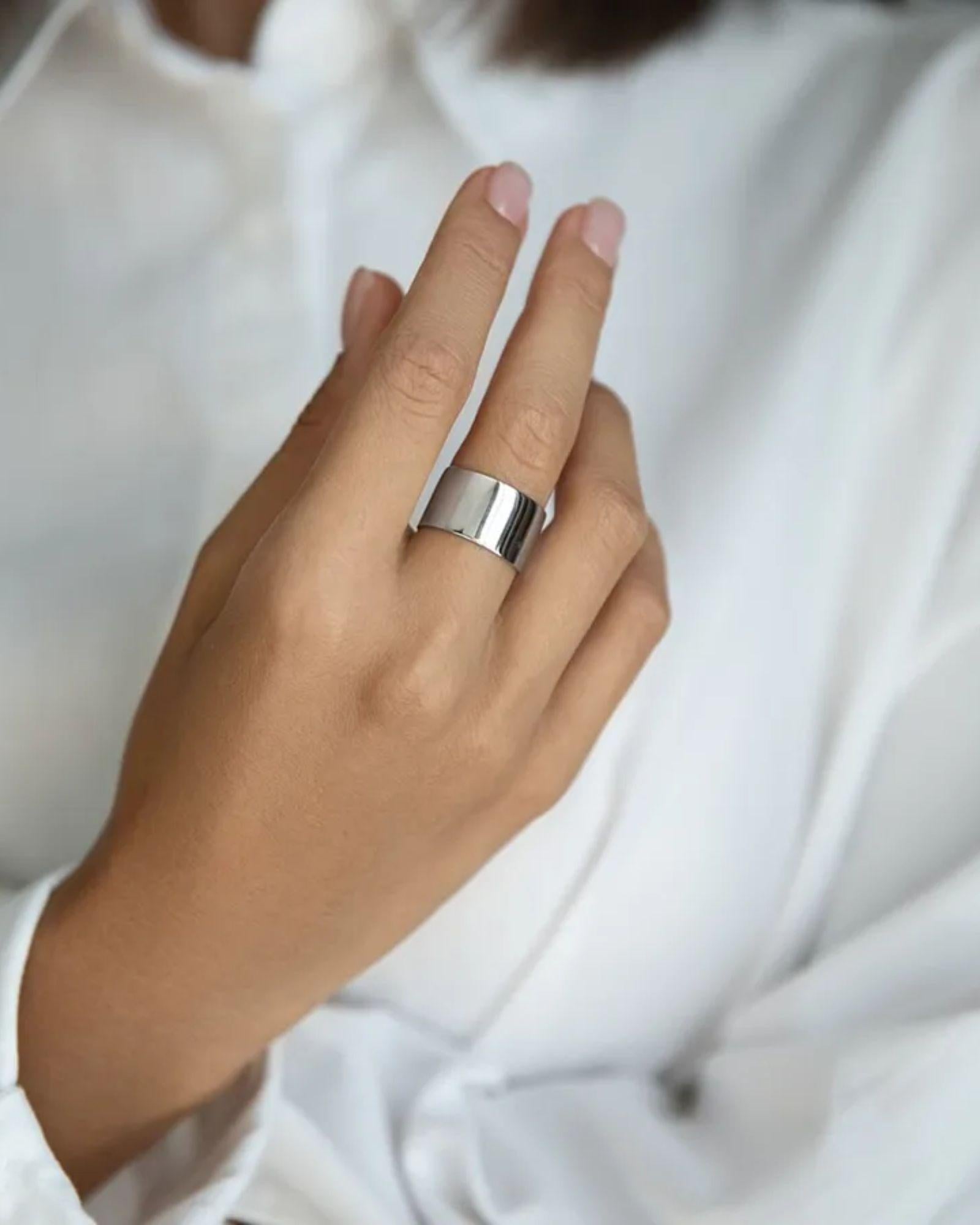 Hand wearing a silver ring with a white background