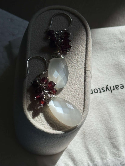 Moonstone and Garnet Cluster earring displayed on a jewellery package