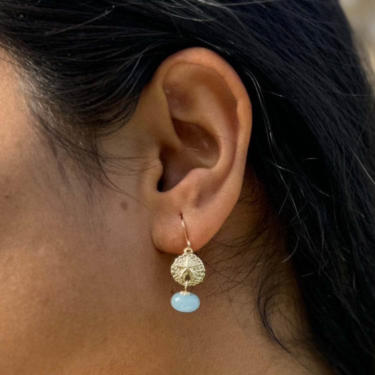 A women wearing a beautiful pale blue chalcedony gemstone earring made in gold filled materials.