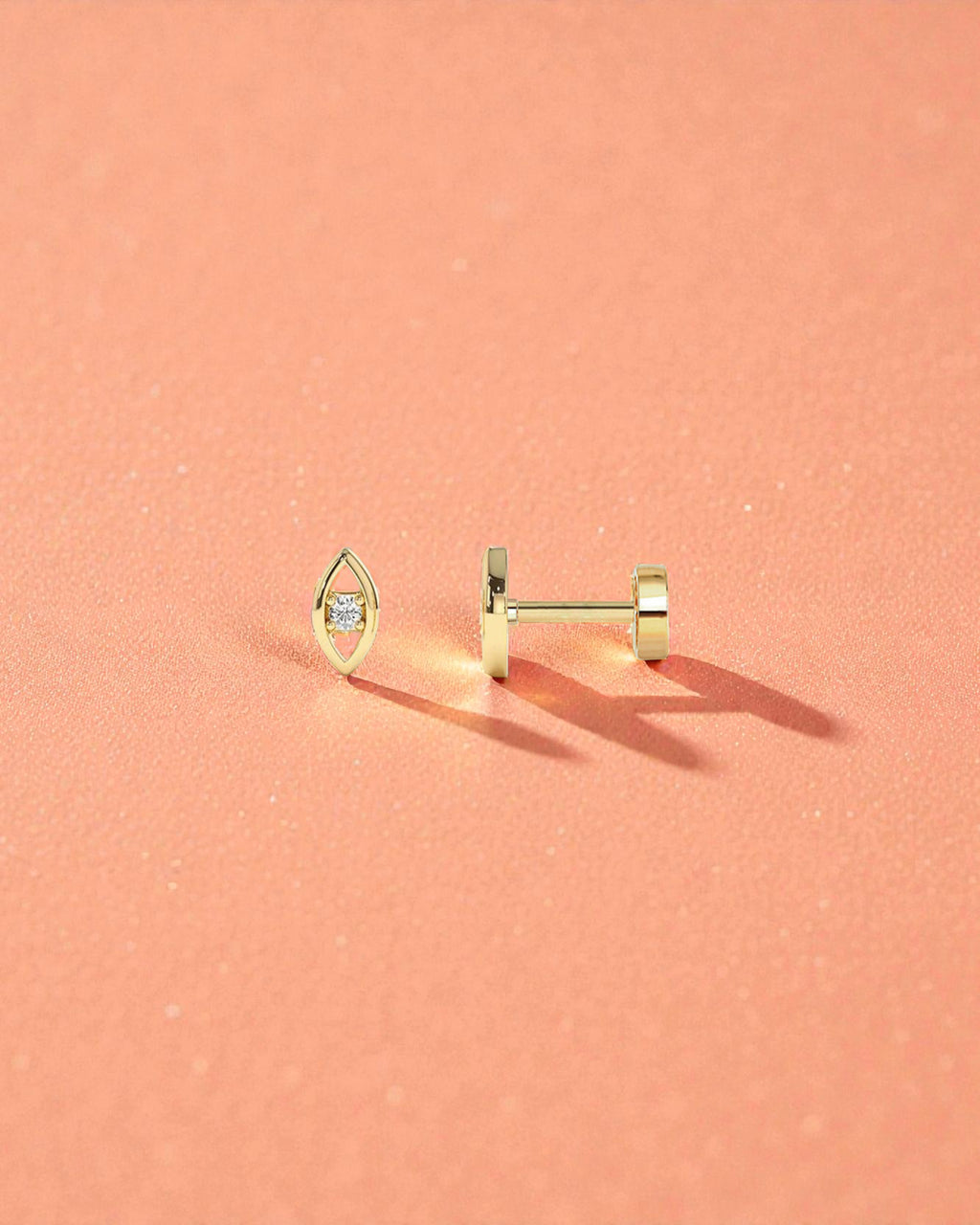 Single Piece Evil Eye Flat Back Cartilage Stud displayed on a soft peach background, showcasing its elegant design.