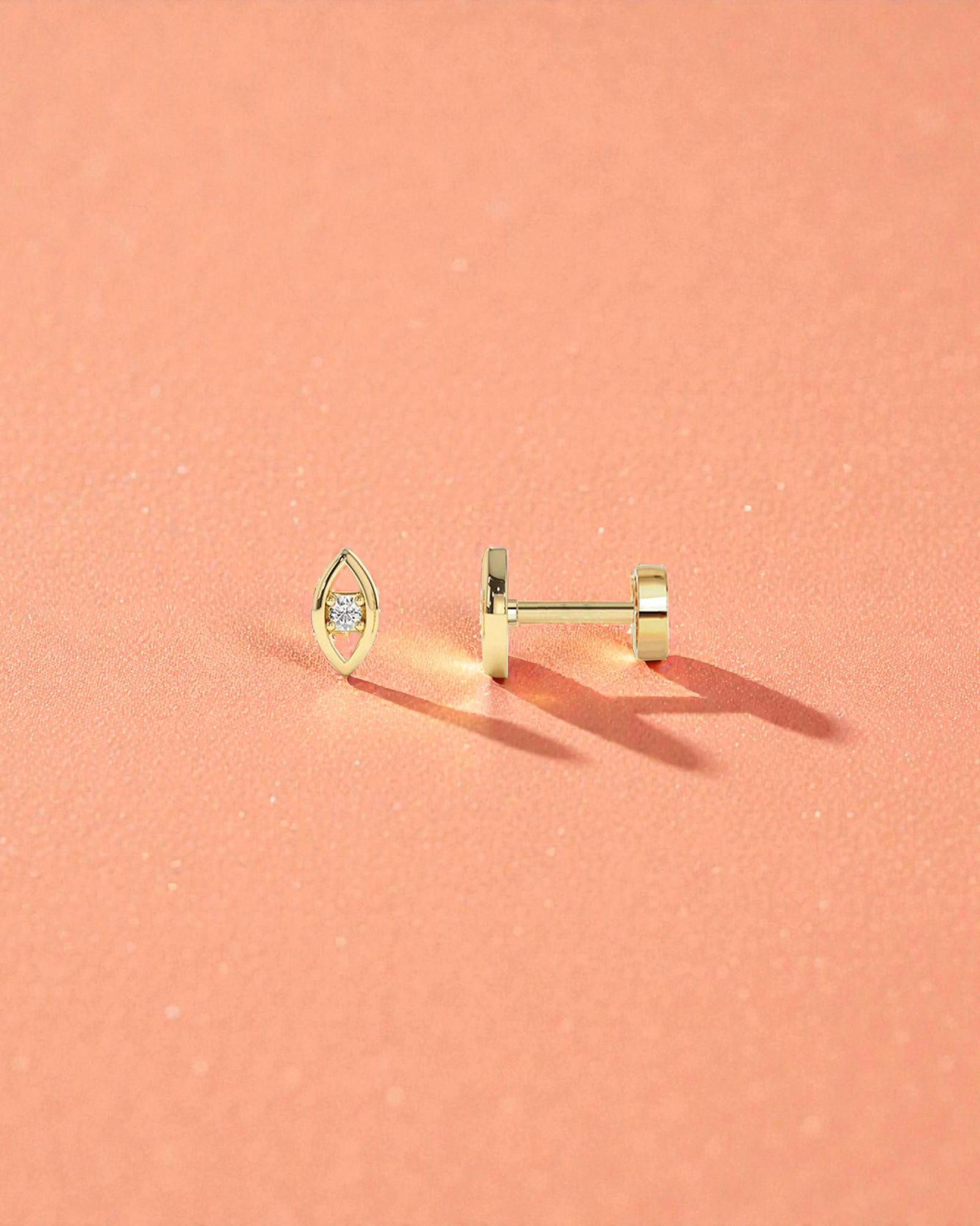 Single Piece Evil Eye Flat Back Cartilage Stud displayed on a soft peach background, showcasing its elegant design.