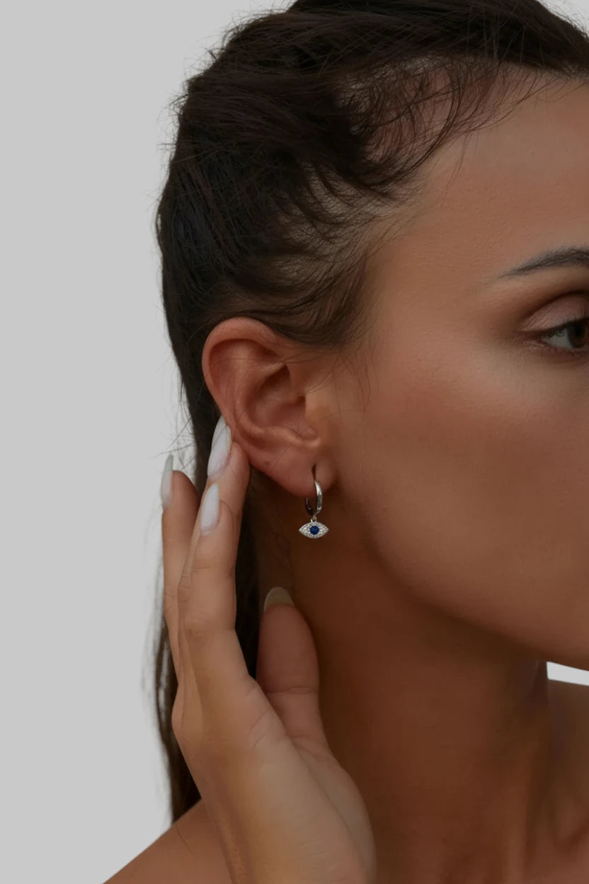 Close-up of a woman wearing an eye-shaped earring with a neutral background