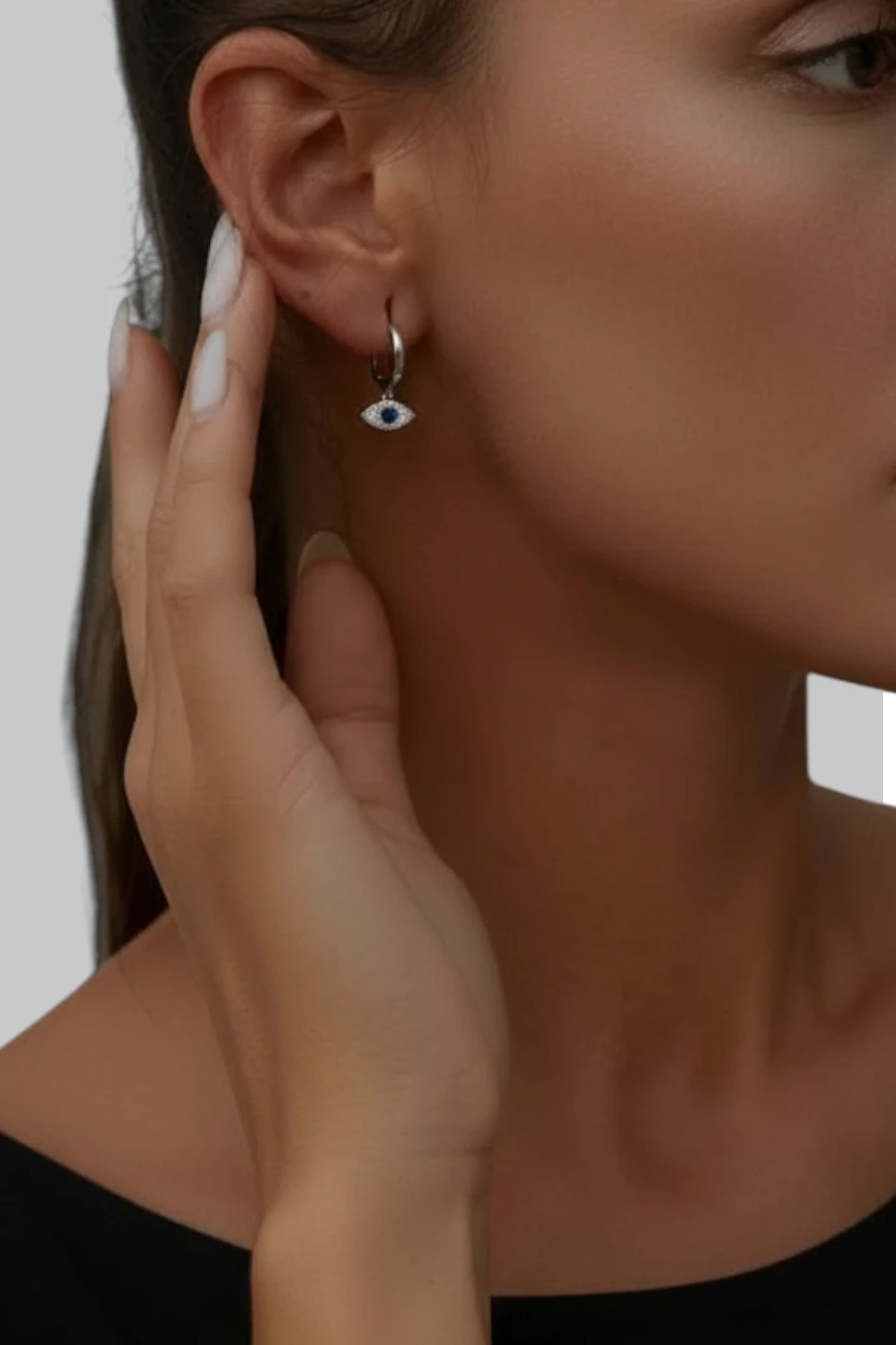 Close-up of a woman wearing an earring with a hand touching her ear.