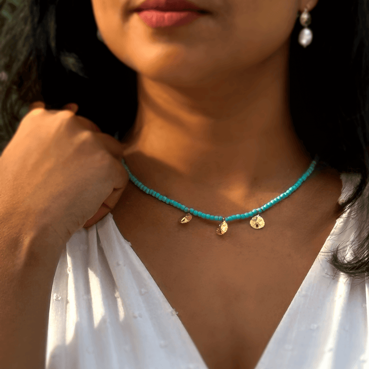 A woman wearing a Turquoise necklace featuring three sand dollar charms