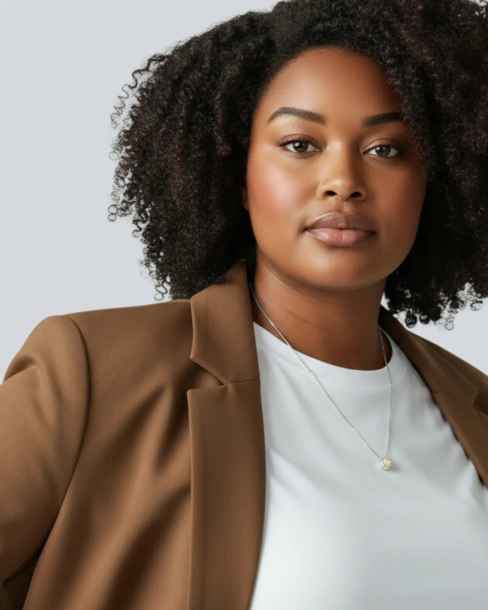Woman wearing an octagonal rose cut yellow zircon pendant necklace in silver with a brown blazer.