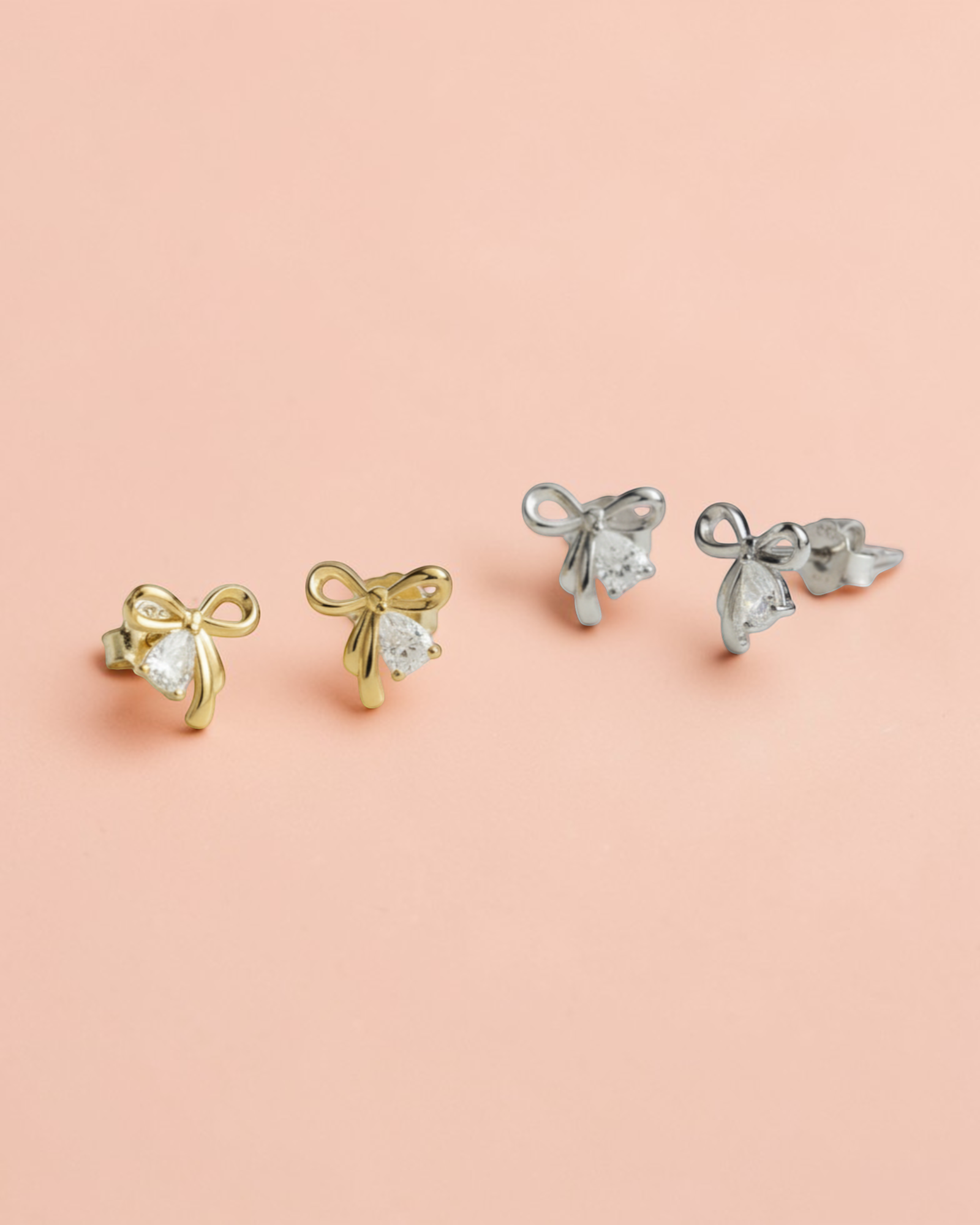Pearlystones gold and silver bowknot stud earrings with pear-shaped zirconia.