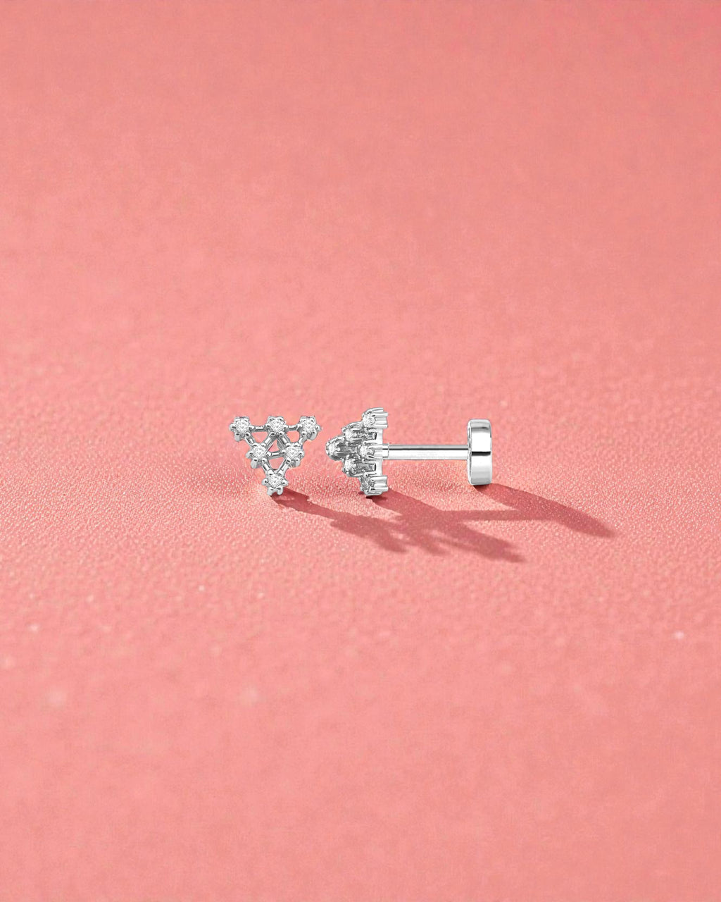 18G Pyramid Flat Back Single Piece Stud displayed on a pink background, showcasing its elegant design and secure fit.
