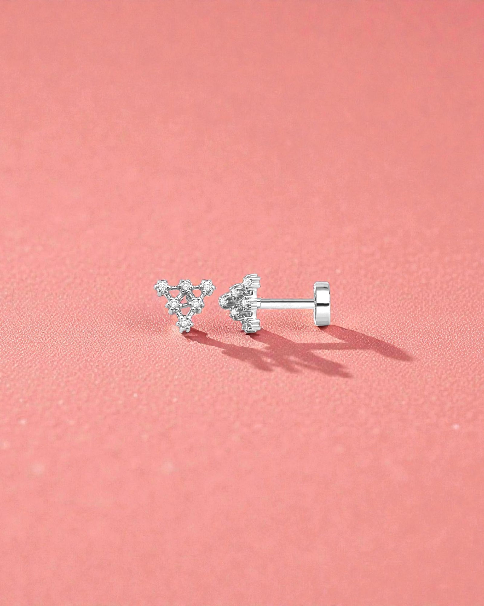 18G Pyramid Flat Back Single Piece Stud displayed on a pink background, showcasing its elegant design and secure fit.