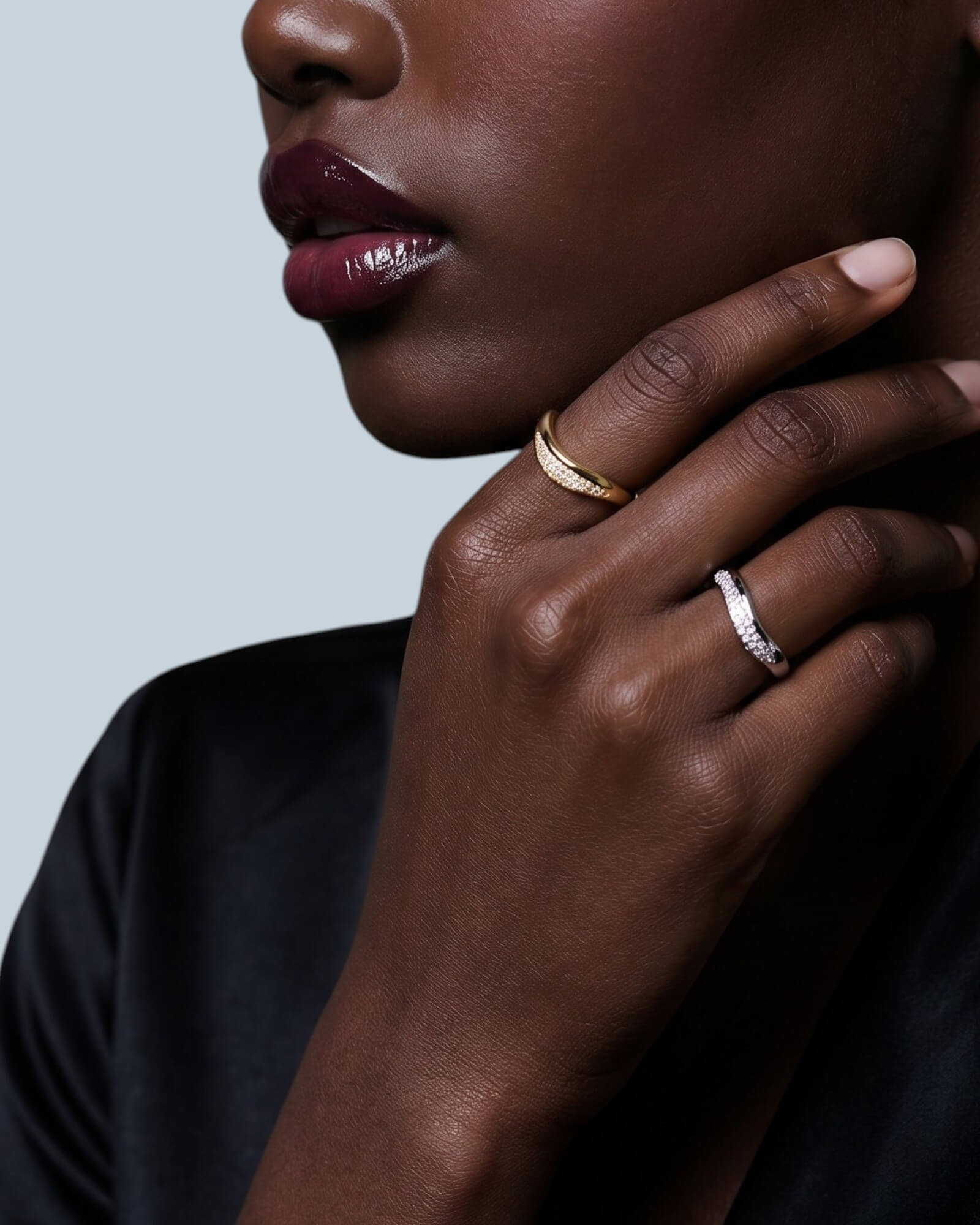 Close-up of a woman's hand with two rings on a light gray background