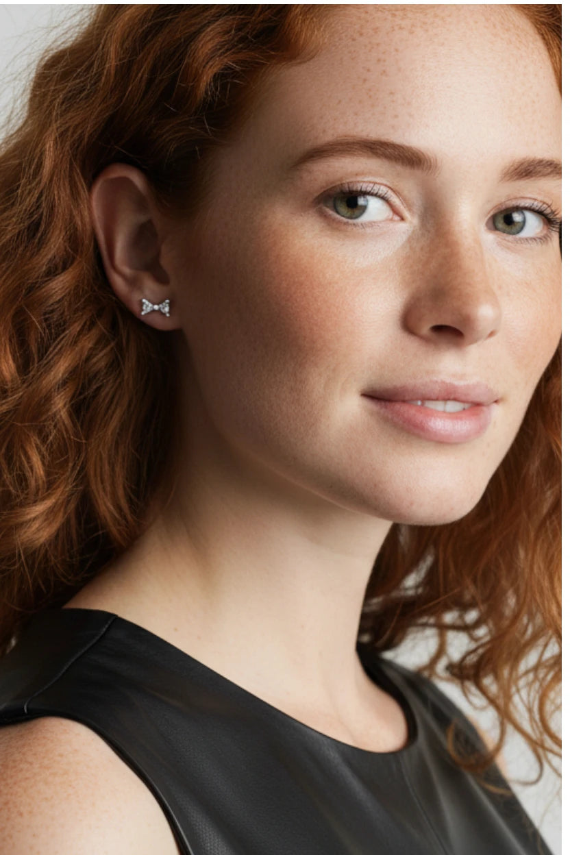 Small Bow Earrings in Sterling Silver worn by a model with curly hair, showcasing a refined look.