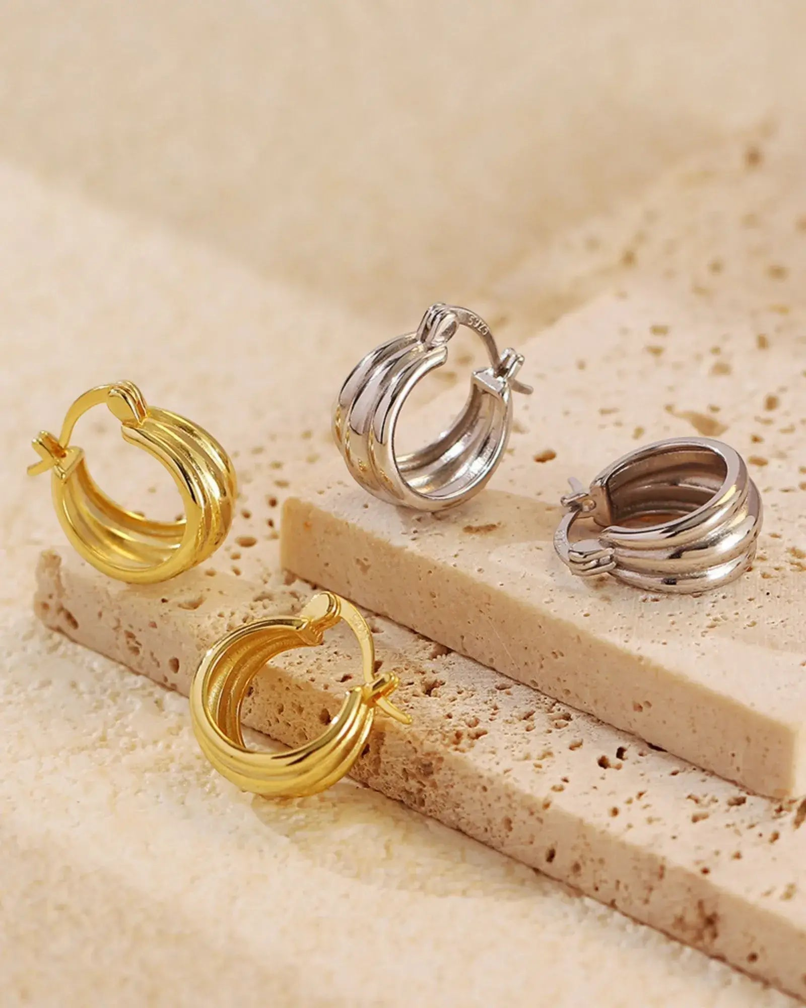 Aura Curve Hoop Earrings in gold and silver, showcasing a sleek sculptural design, perfect for any jewelry lover.