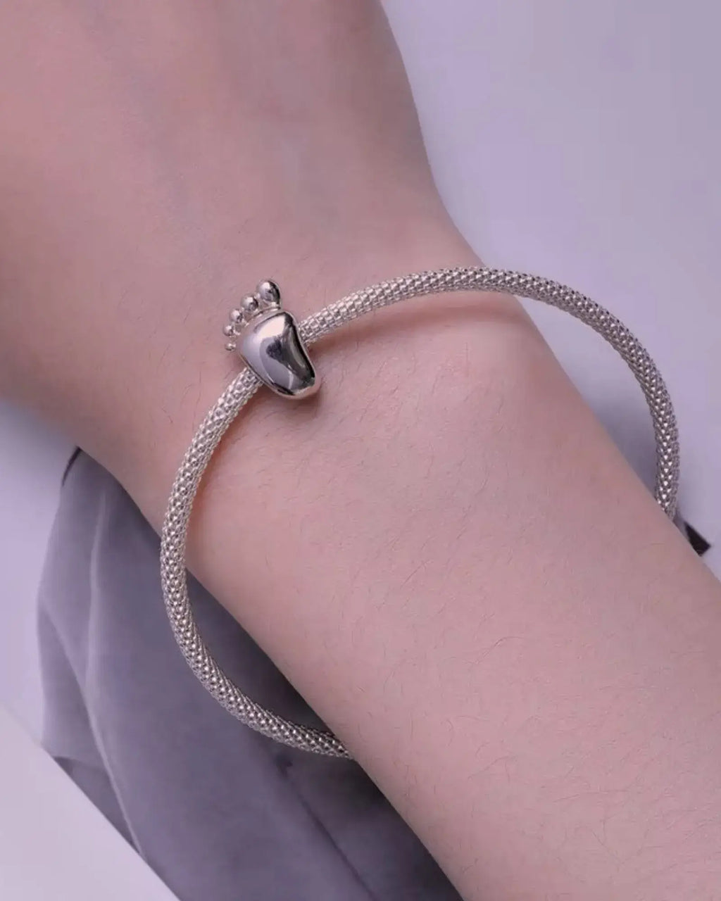 Engravable Baby Feet Charm on a silver bracelet, showcasing high-quality sterling silver craftsmanship.