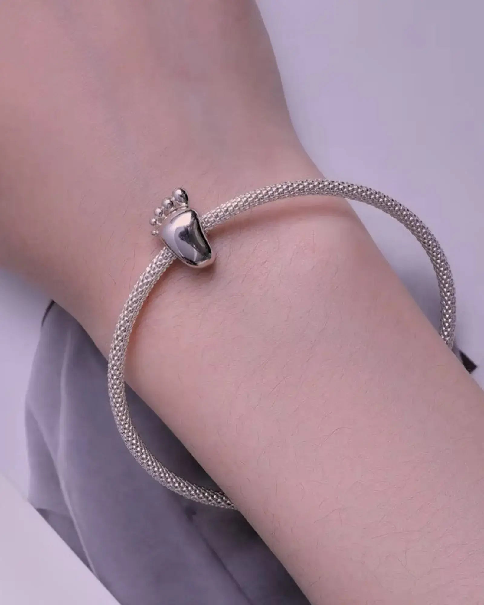 Engravable Baby Feet Charm on a silver bracelet, showcasing high-quality sterling silver craftsmanship.