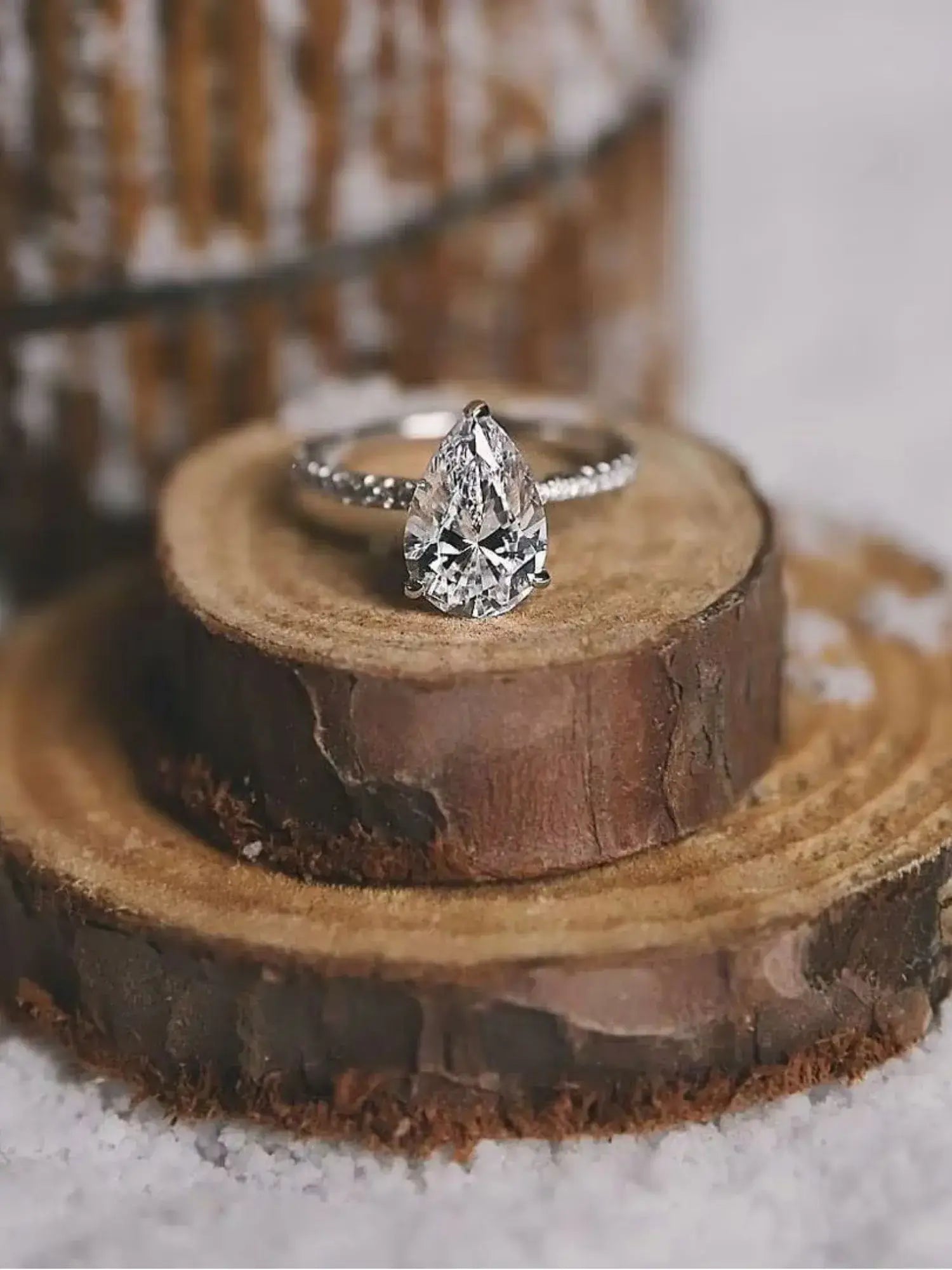 Golden Promise Engagement Ring featuring a water drop-shaped cubic zirconia on a wooden slice background.