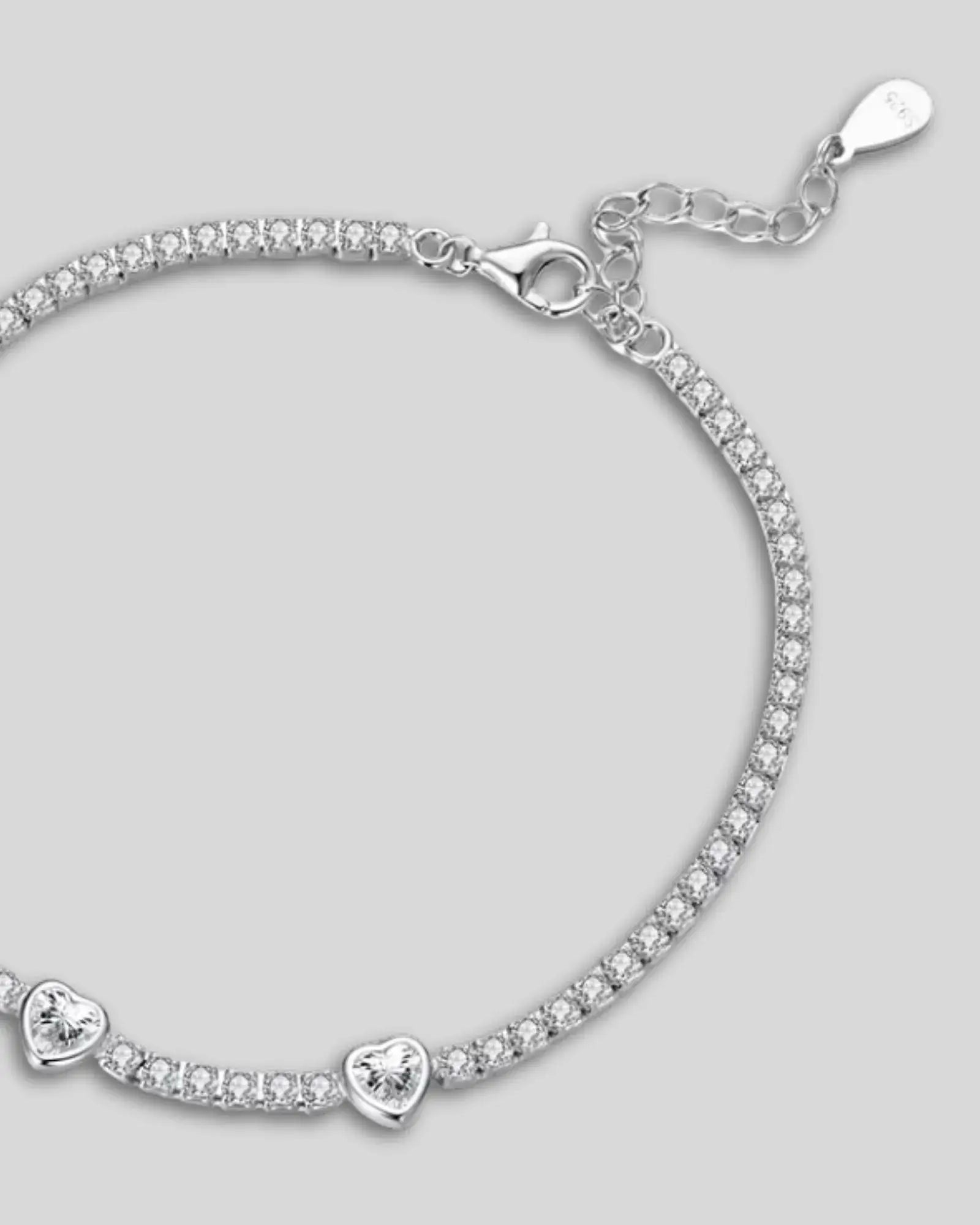 Heart tennis bracelet in 925 sterling silver with white gold plating and cubic zirconia accents.