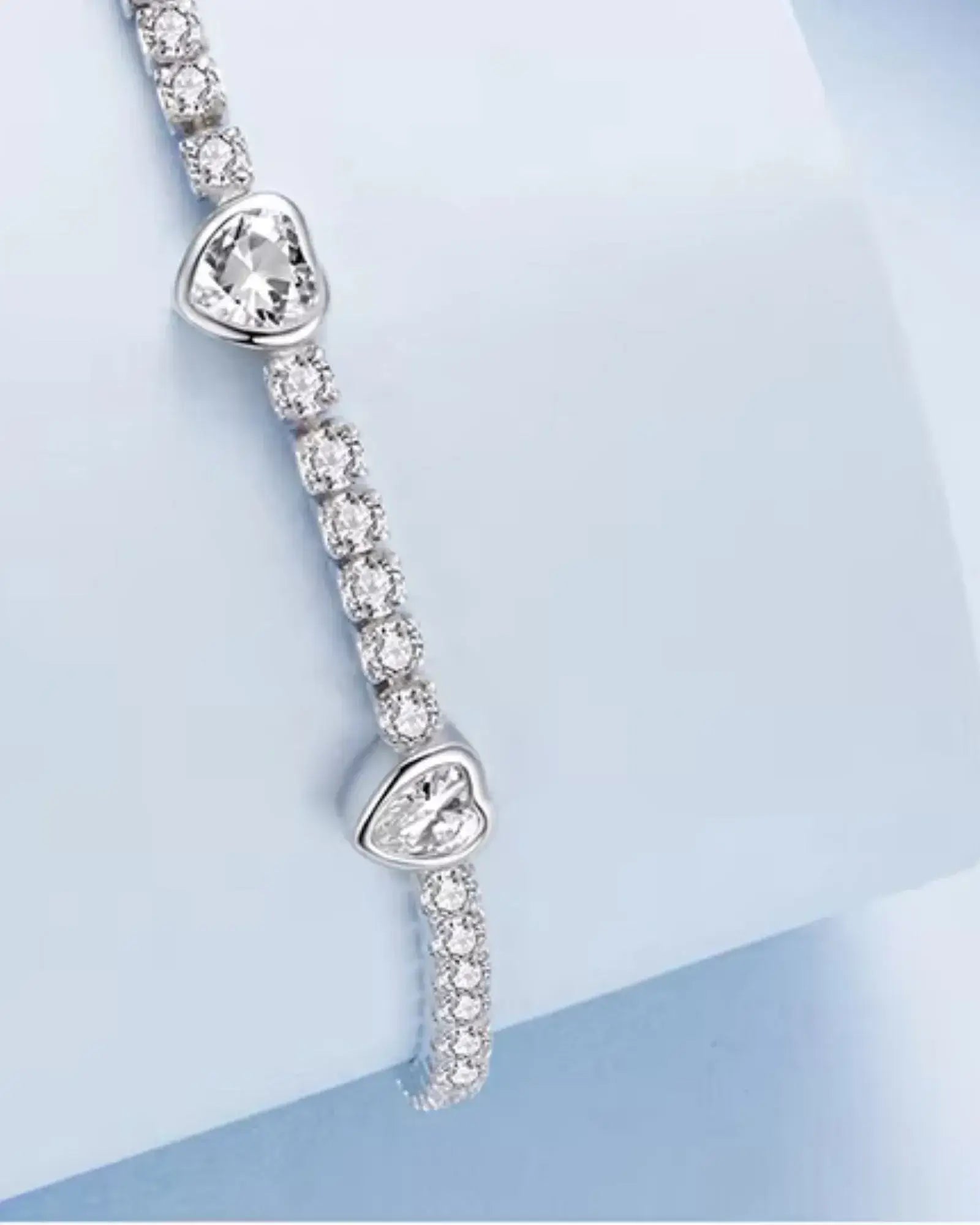 Heart tennis bracelet in 925 sterling silver with white gold plating and sparkling cubic zirconia stones.
