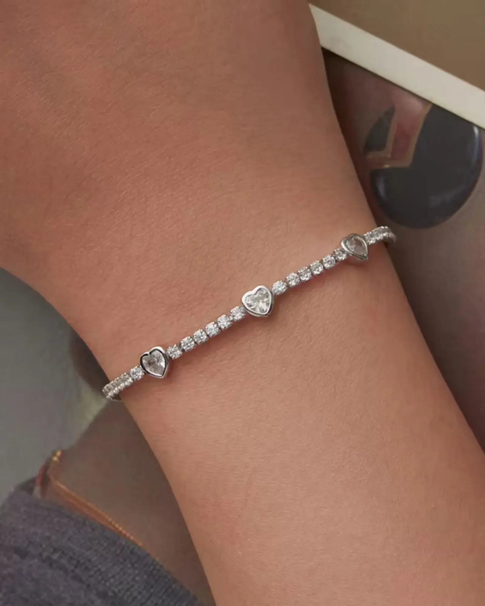 Elegant heart tennis bracelet in sterling silver with cubic zirconia accents, worn on a wrist for a sophisticated touch.