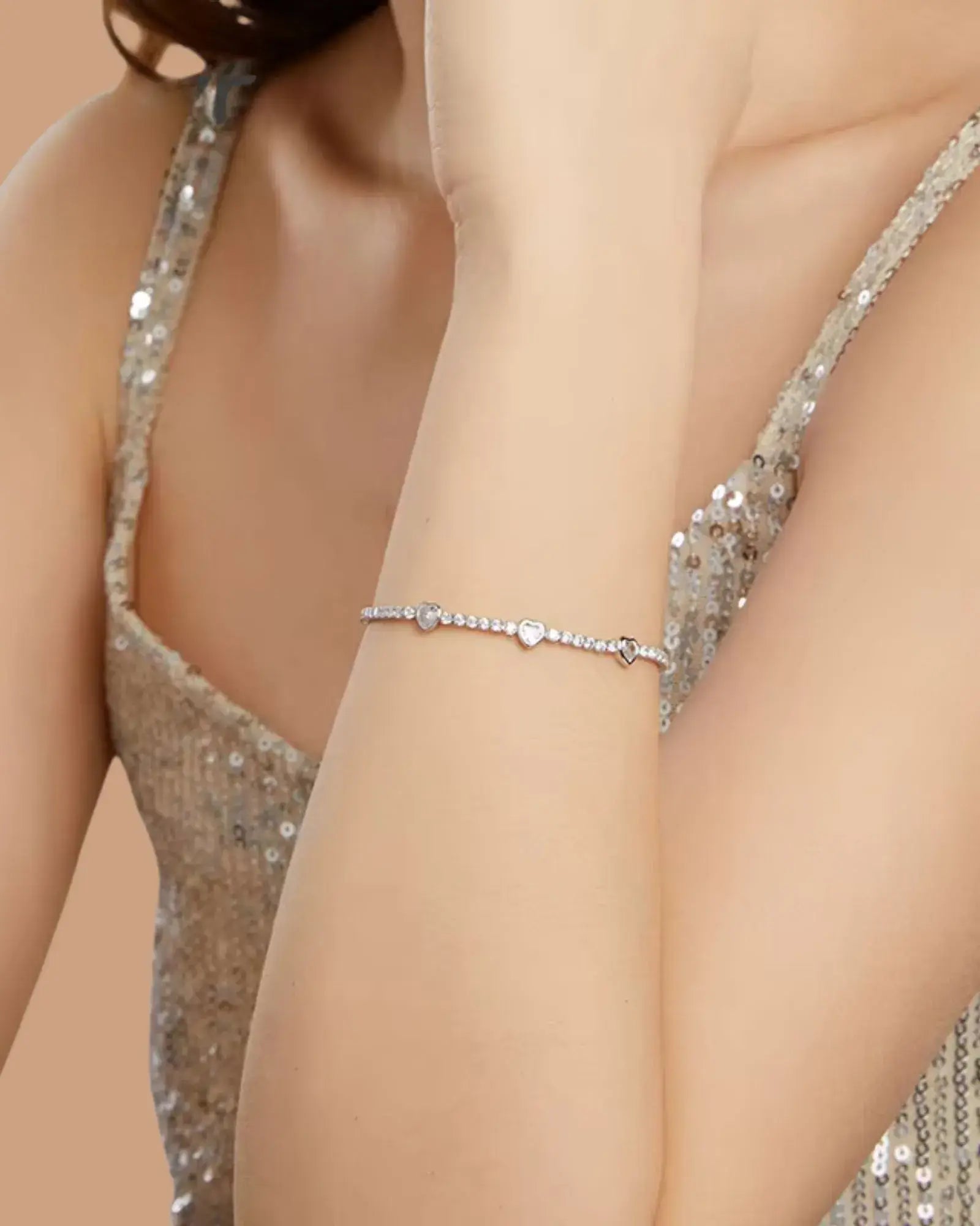 Heart tennis bracelet in 925 sterling silver with white gold plating and cubic zirconia, worn on a sparkling dress.