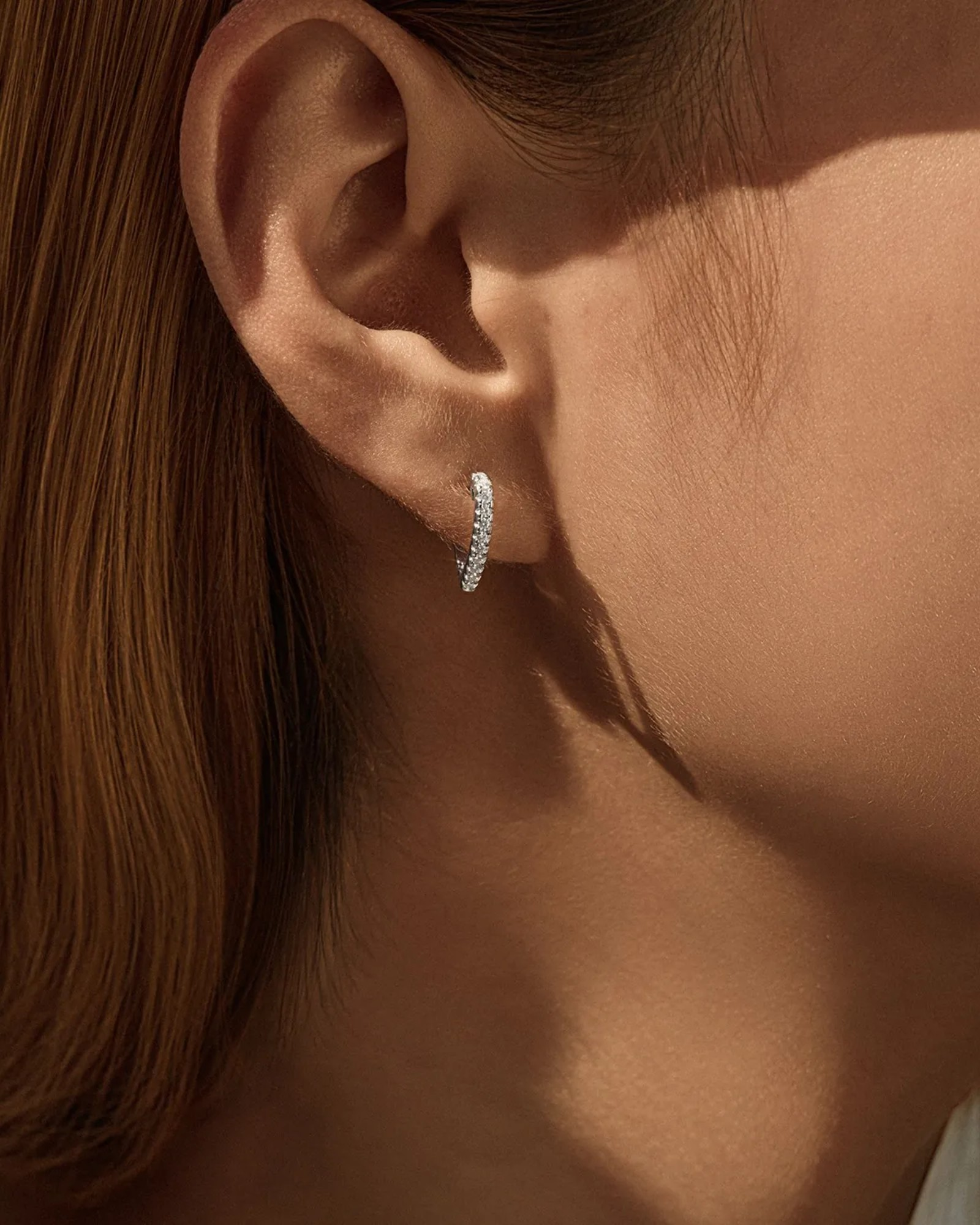 0.2 Ct Moissanite Heart shaped hoops worn in an ear, showcasing their brilliant sparkle and heart shape.