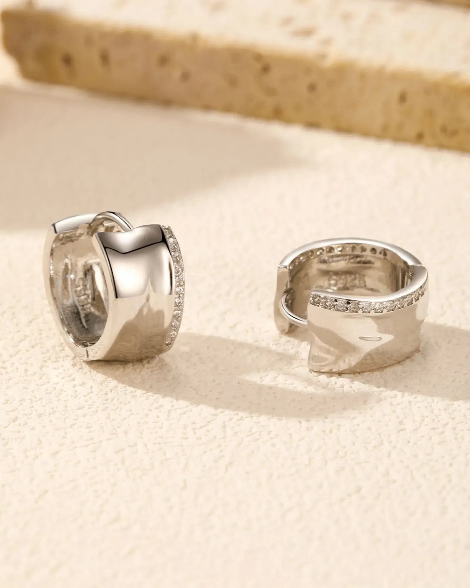 Irregular small zircon hoop earrings in sterling silver with rhodium finish and pavé-set zirconia for elegant styling.