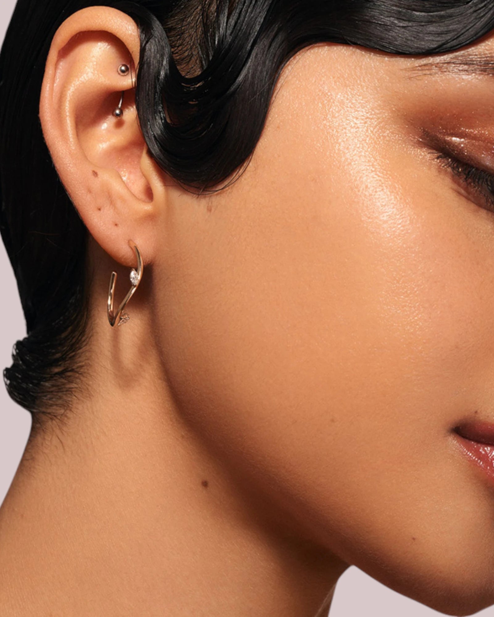 Close-up of a model wearing Irregular Half Hoop earring with marquis-shaped zirconia stones.
