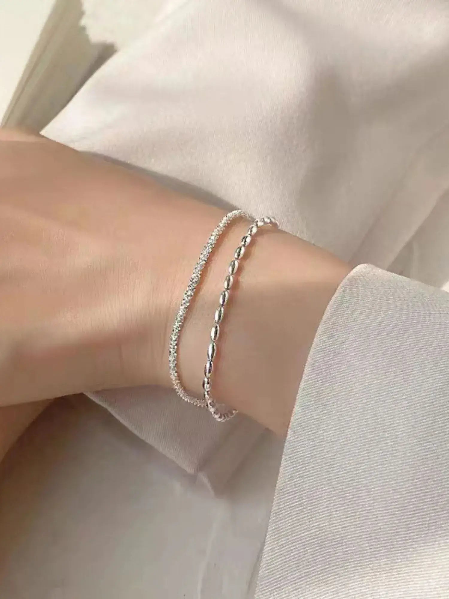 Silver bracelet on a wrist with a light background