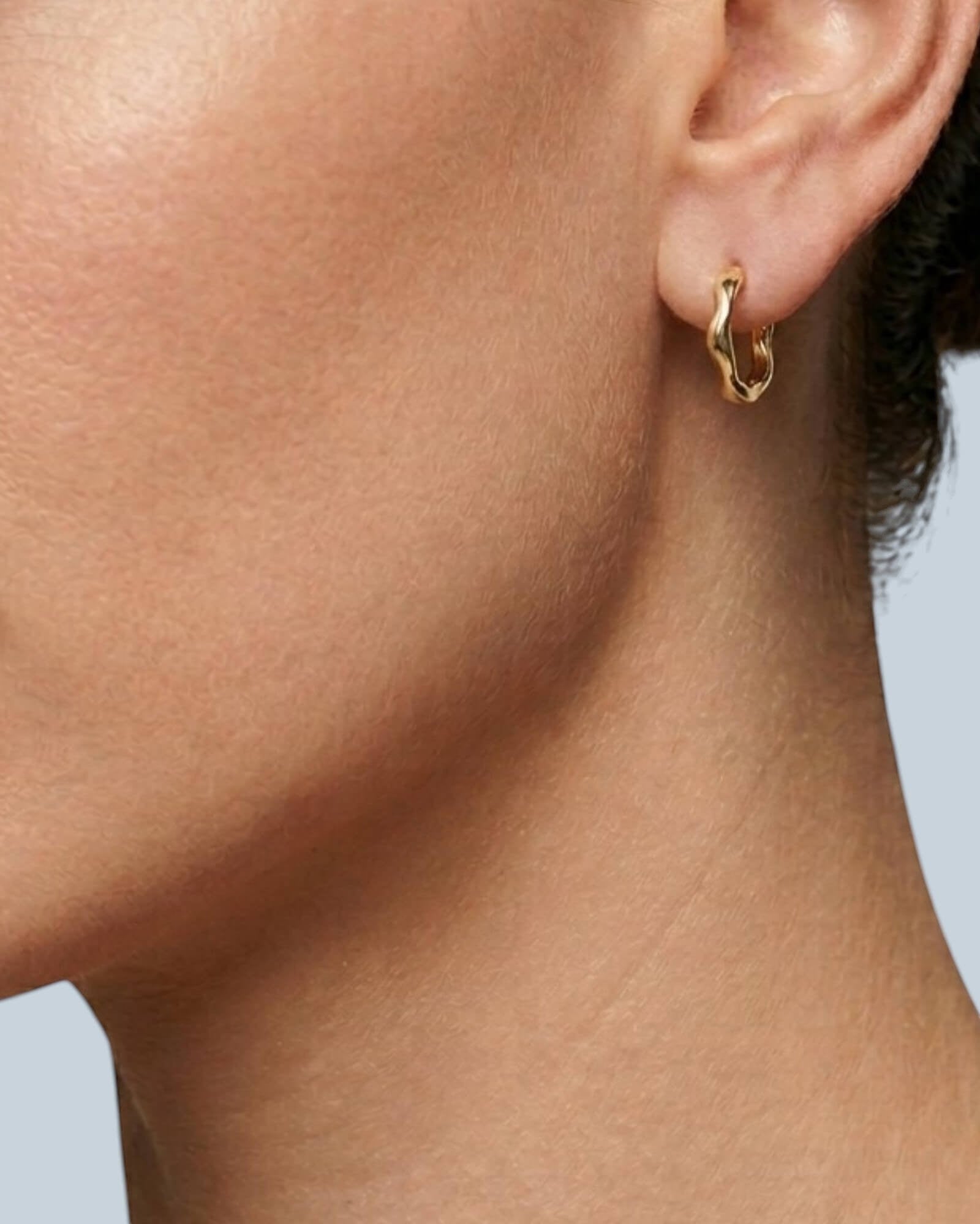 Pearlstones medium gold hoop earrings with a molten, undulating texture and hinged closure.