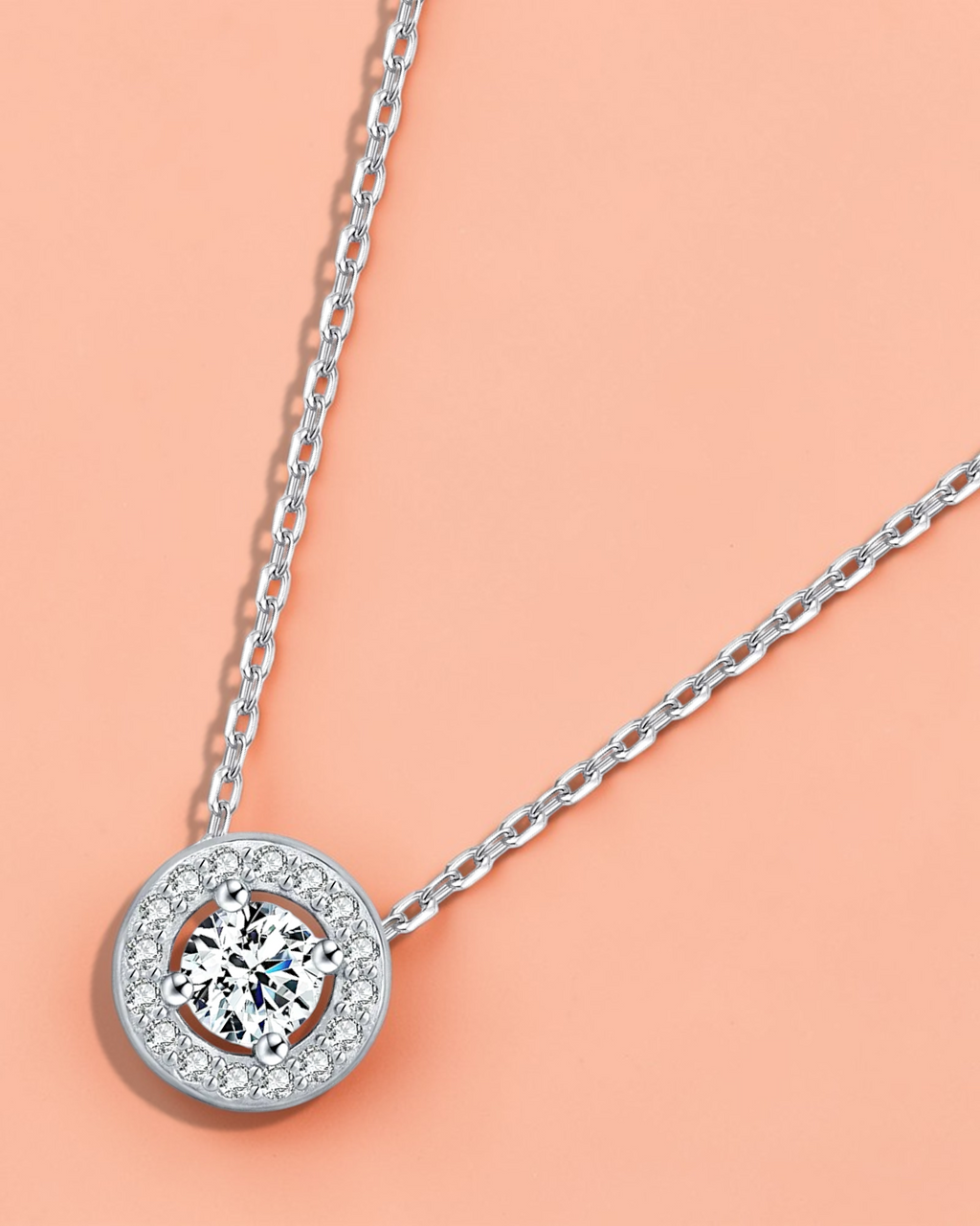 0.5 Ct Round brilliant Cut moissanite necklace on a delicate silver chain against a soft pink background.