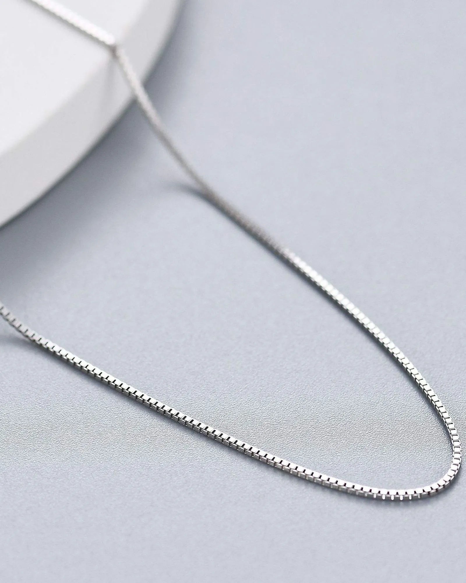 Pearlystones 0.6mm box chain necklace in sterling silver with a lustrous platinum finish on a grey background