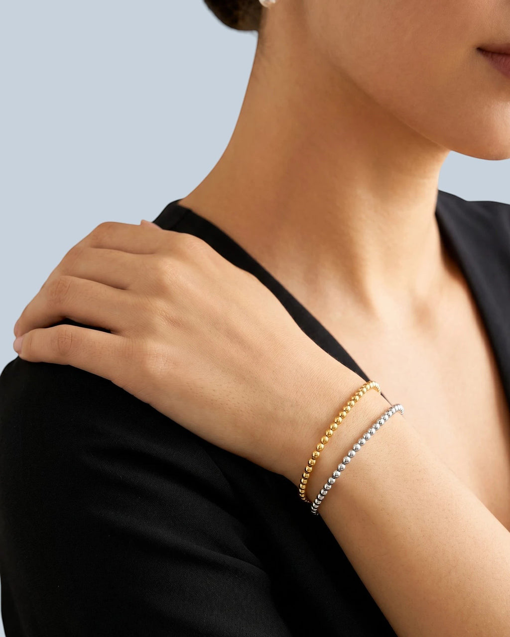 Pearlystones gold-tone and silver-tone beaded chain bracelets worn on a woman's wrist. Delicate, uniform beads.