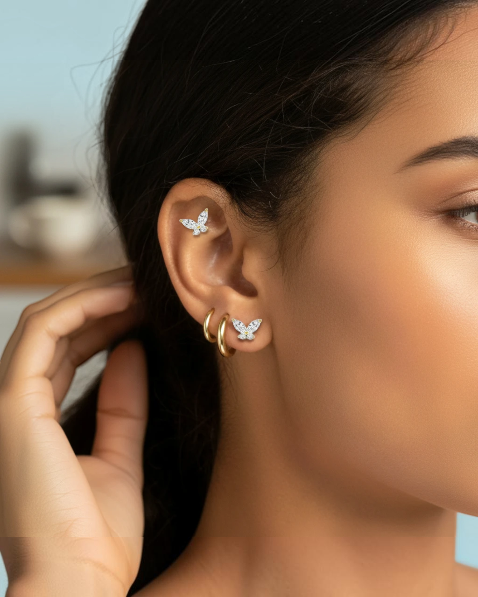 Pearlystones butterfly cartilage stud with zircon stones worn on a woman's ear with gold hoop earrings
