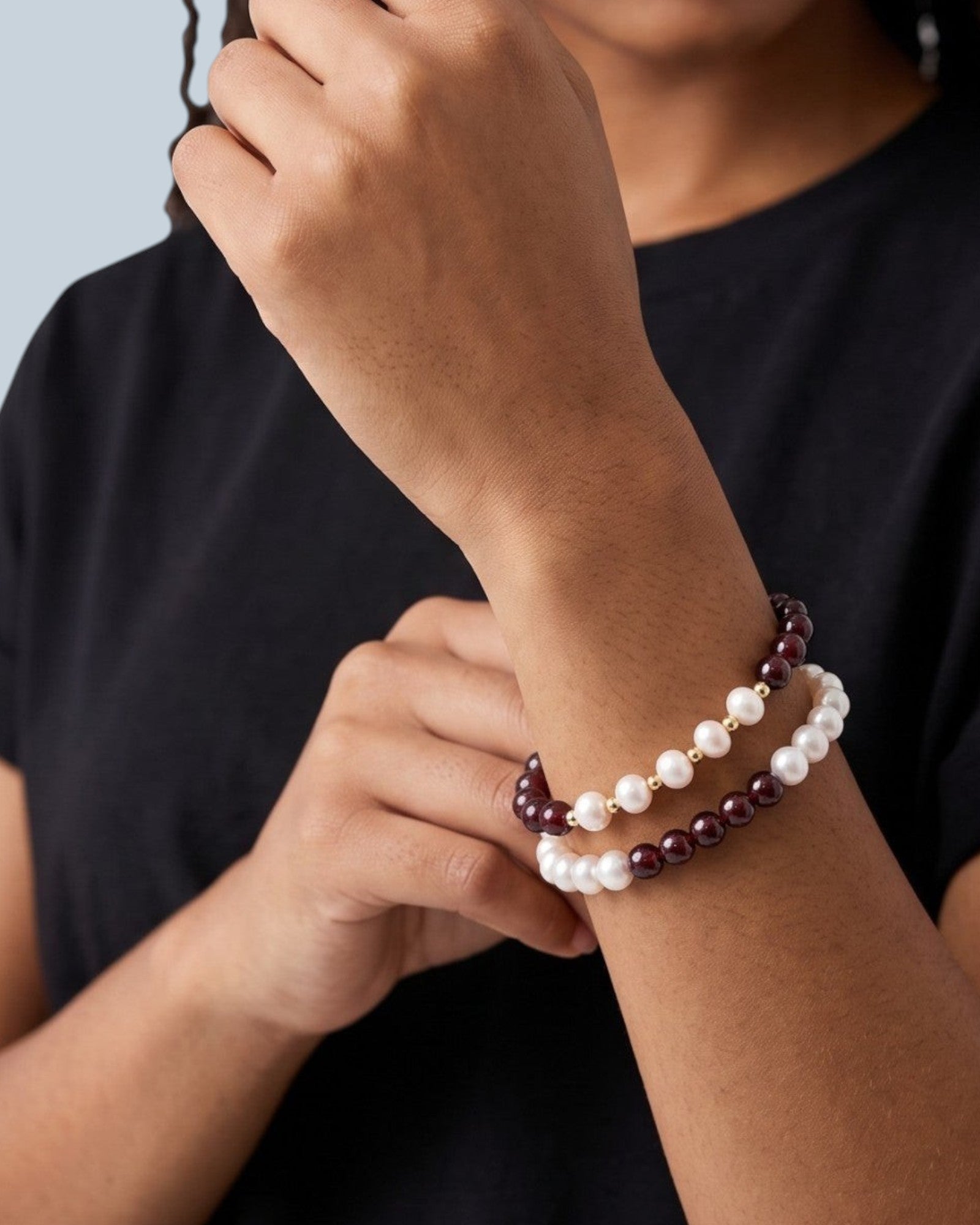 Pearlystones beaded bracelet featuring white pearls and deep red garnet gemstones with gold spacers on a model.